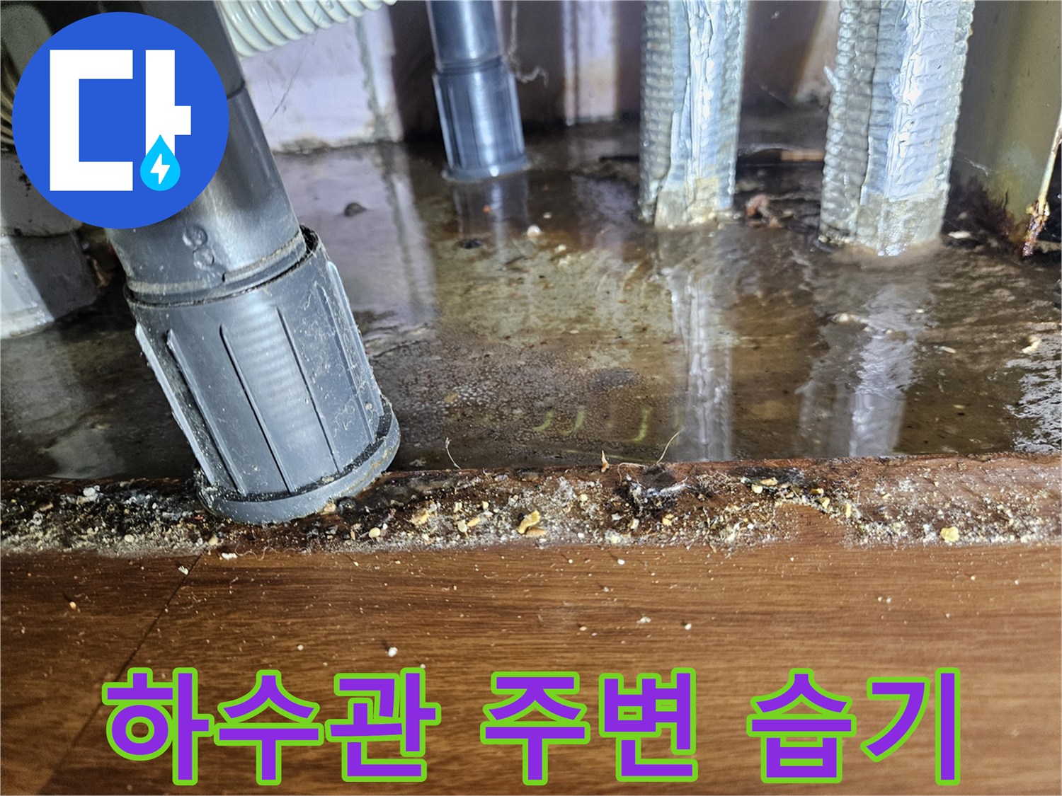 습기가 가득한 하수구 배관 연결 부위와 젖은 마루