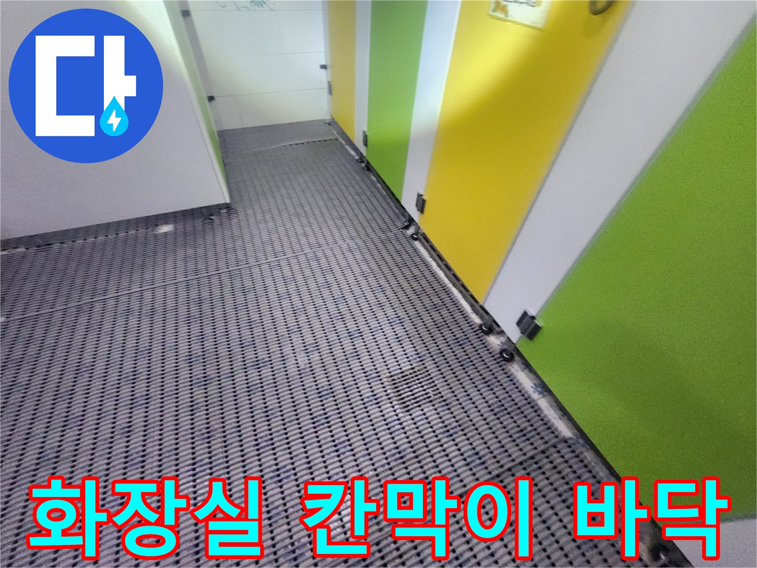 노란색과 초록색 파티션 아래의 화장실 타일 바닥 전경