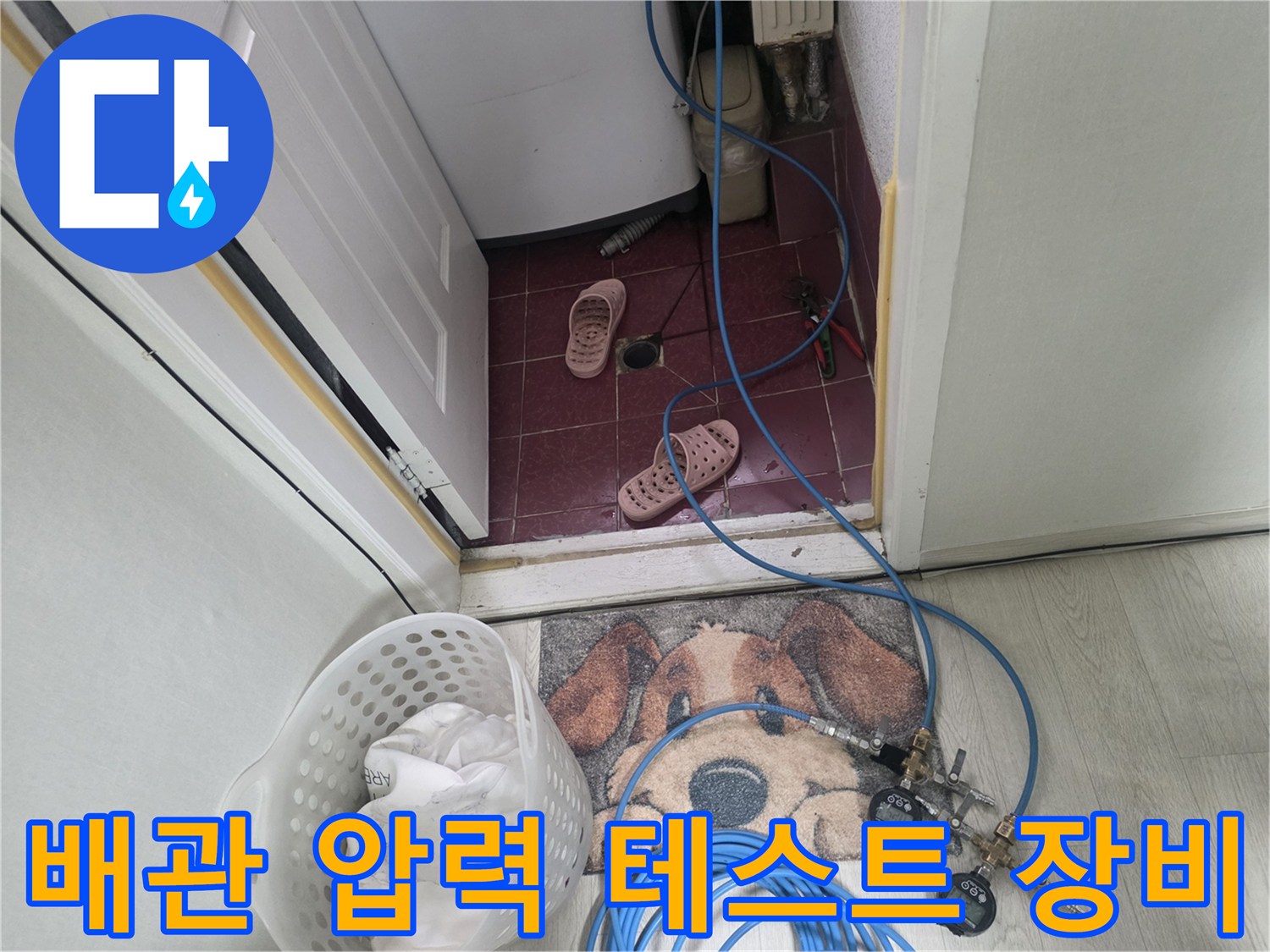 바닥 타일 위에 설치된 파란색 호스와 연결용 밸브 부품들