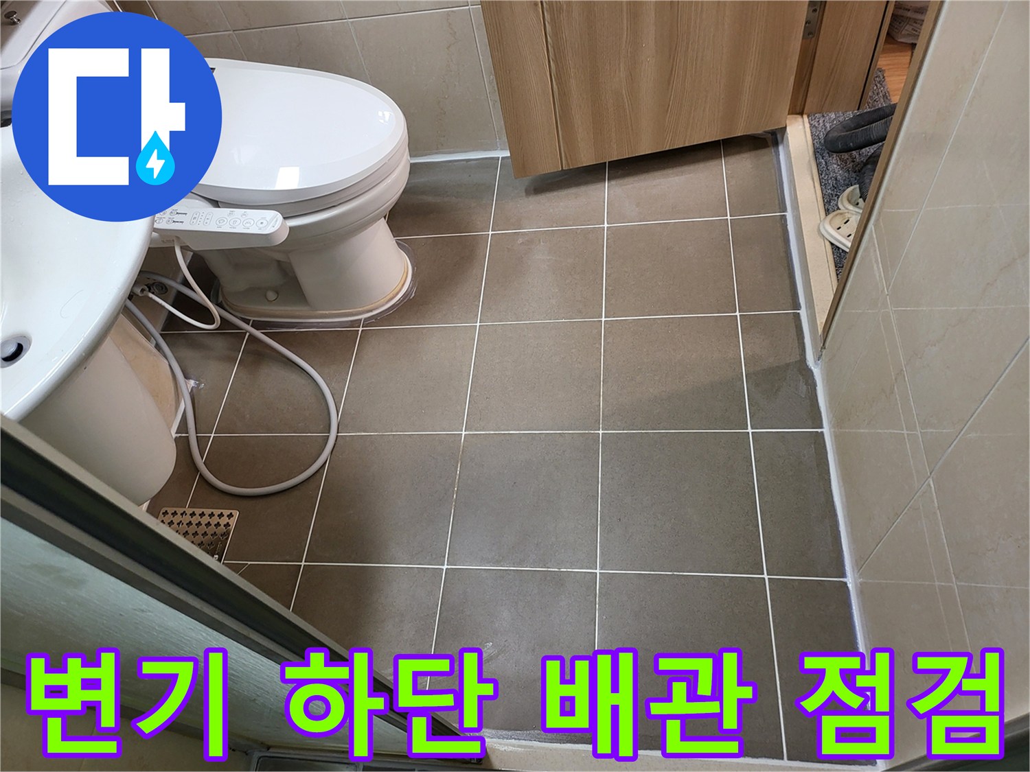 화장실 변기 주변-바닥 타일과 배관 연결 상태를 촬영한 사진입니다.