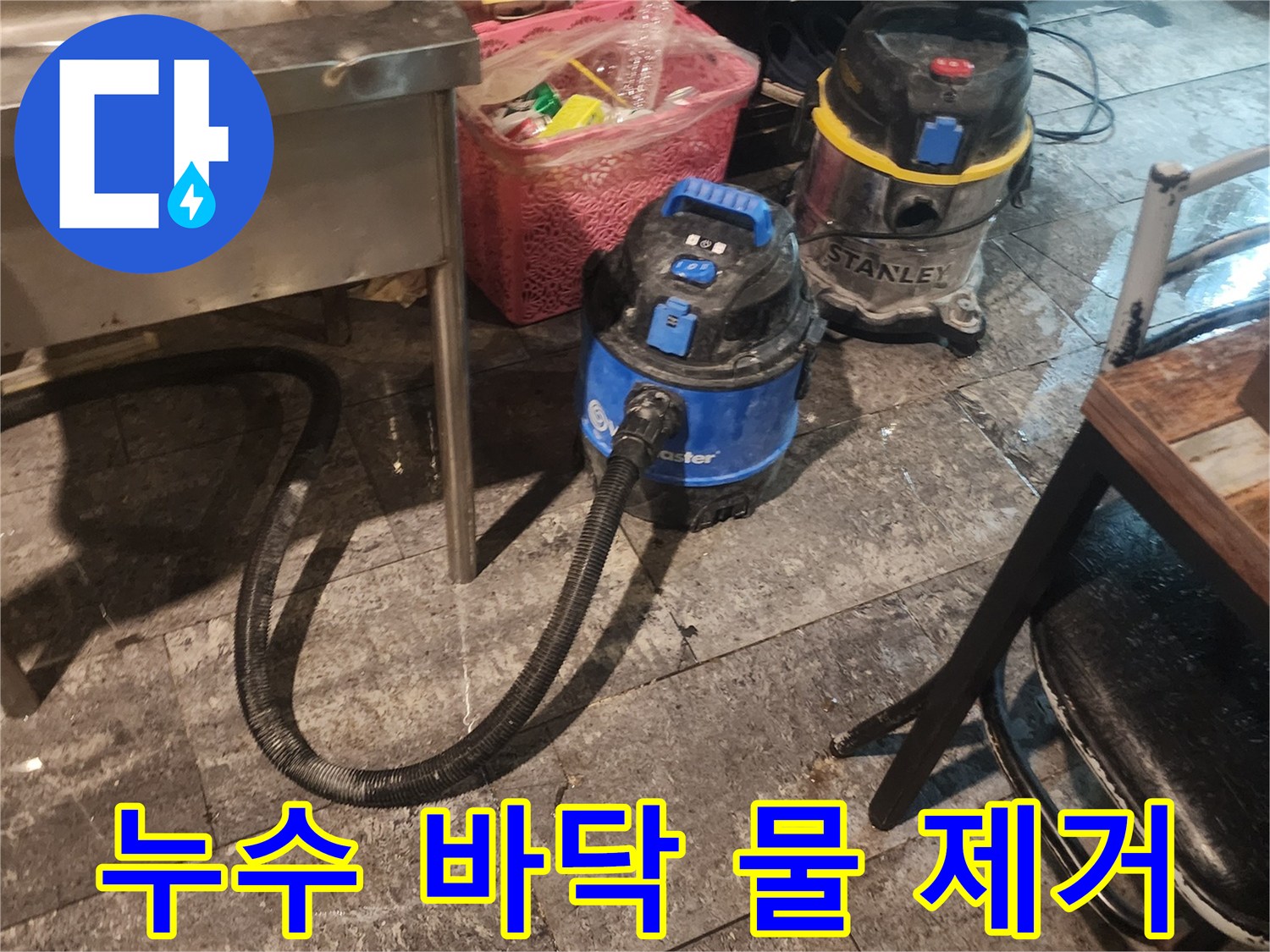누수 현장에서-바닥에 고인 물을-신속하게 흡입하여-건조시키는 데-사용되는-전문 석션 장비 두 대가-작업 대기 중인 모습입니다.