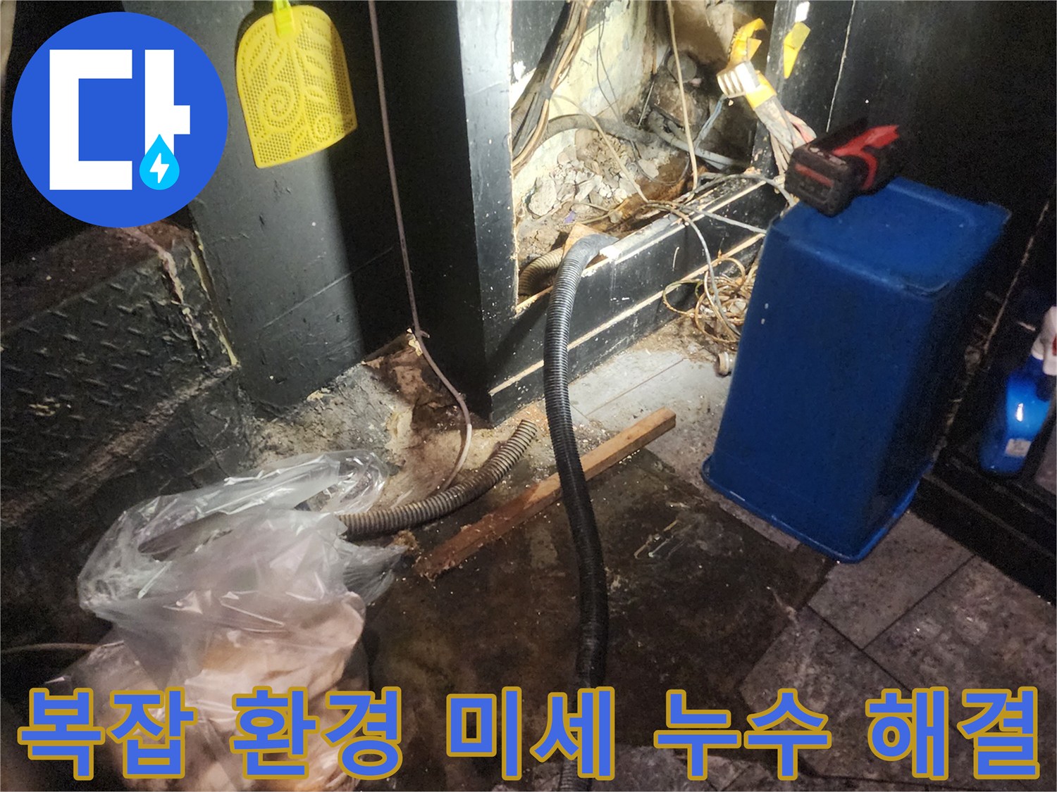어둡고 협소한 공간에서 복잡하게 얽힌 배관과 전선-그리고 물이 고여있는 바닥을 보여주며 누수 탐지 작업을 진행하는 현장