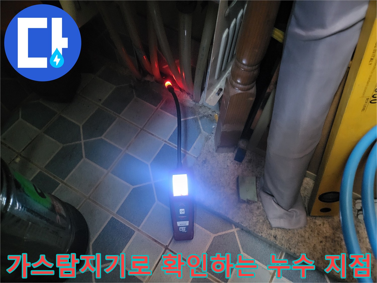 가스 탐지기-밝은 조명 아래 배관 주변을 비추며 누수 위치를 찾는 모습