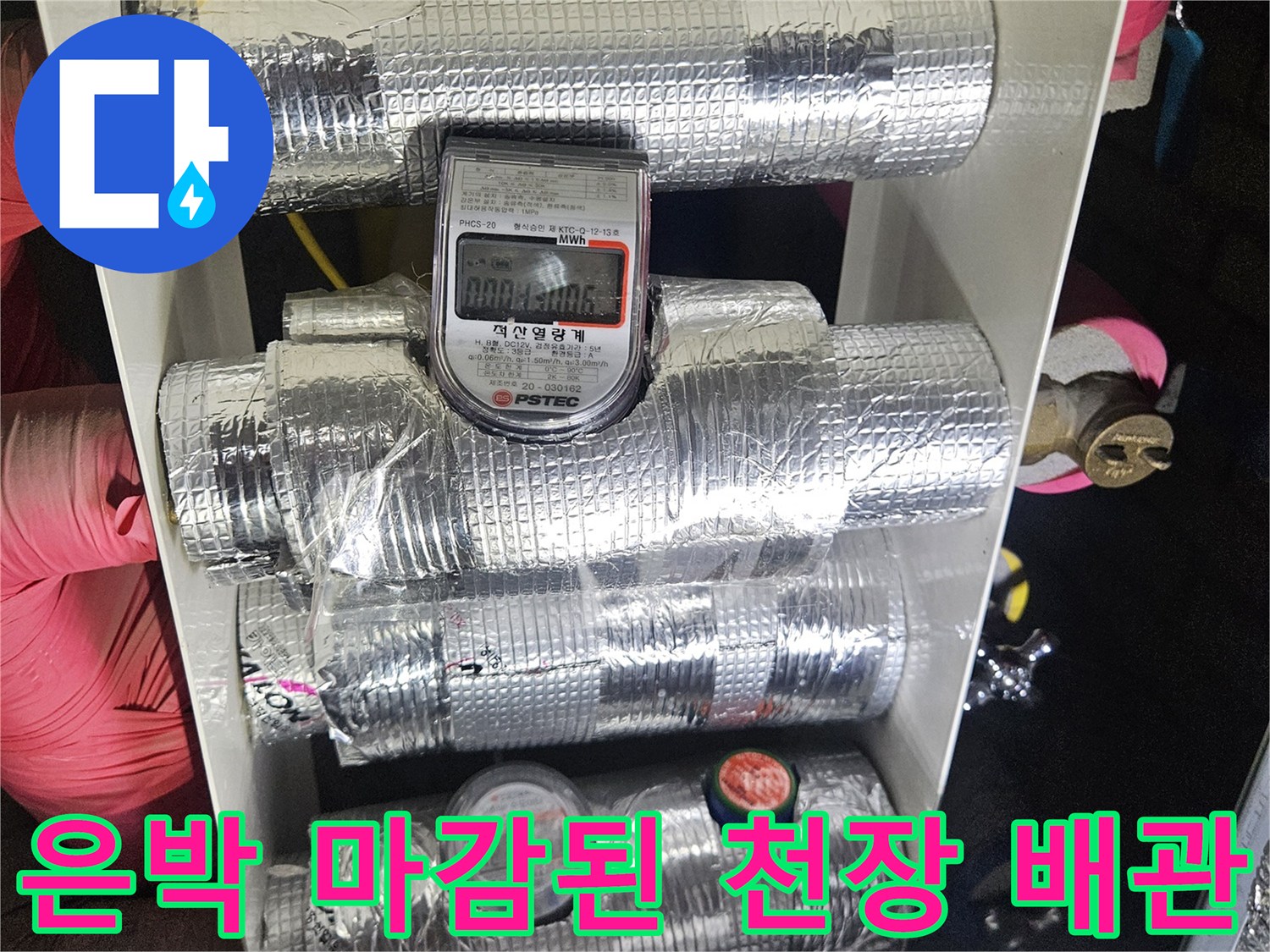 화장실 천장 점검구 내부의 은박 보온재 배관과 수도 계량기 모습