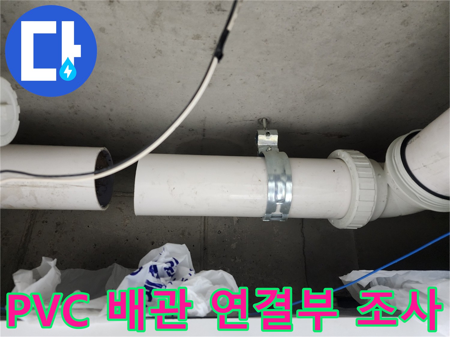 콘크리트 천장에 설치된 흰색 배관과 금속 고정 밴드