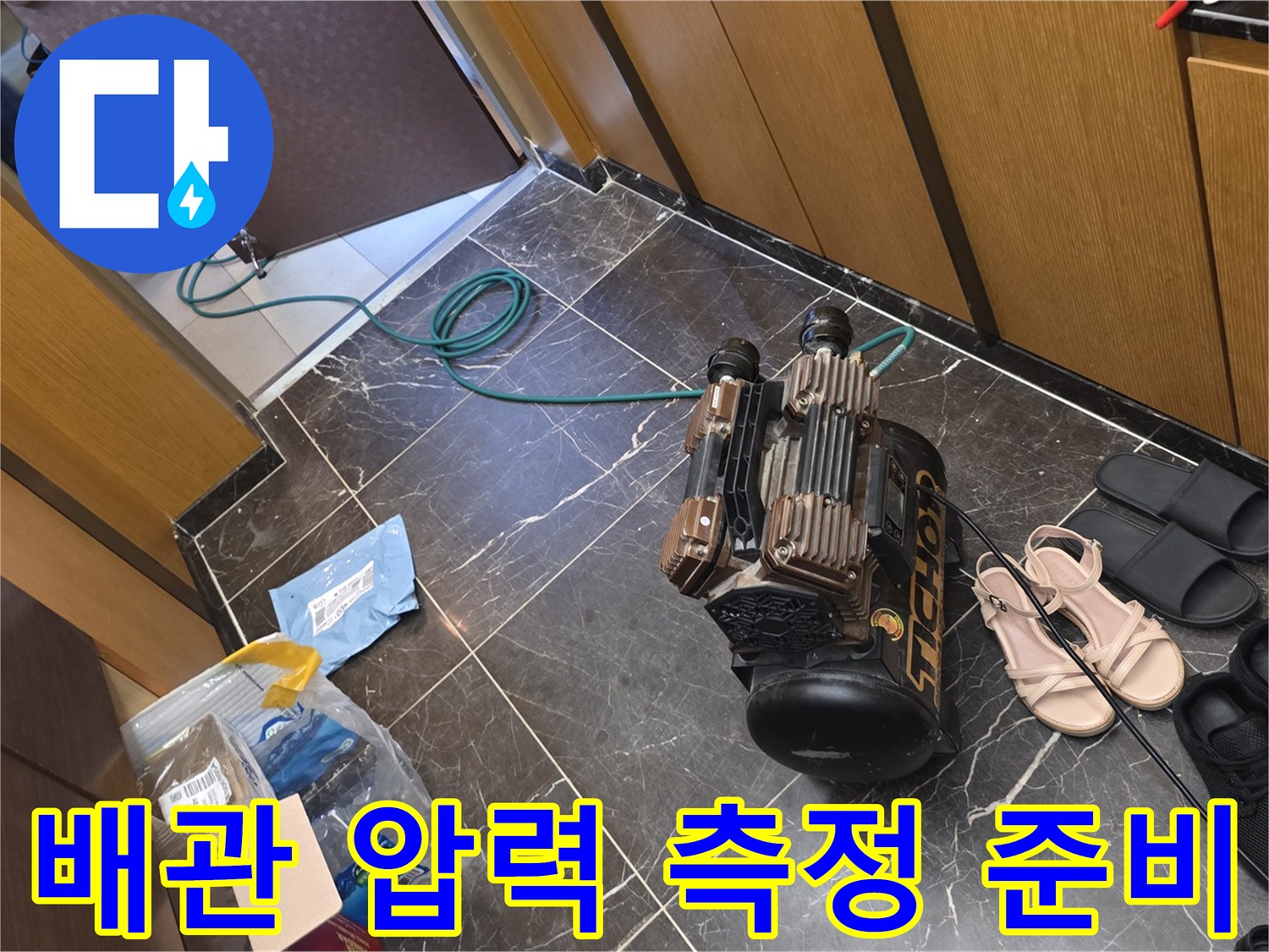 바닥에 놓여 있는 누수 탐지용 압력계와 연결 호스 세트