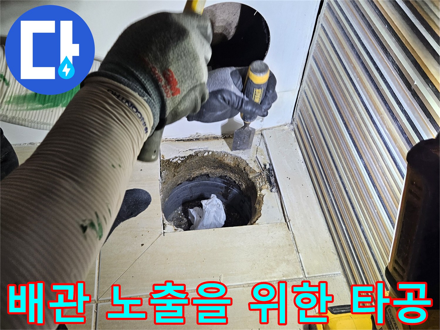 타공된 틈새로 보이는 하수 배관과 작업 도구들