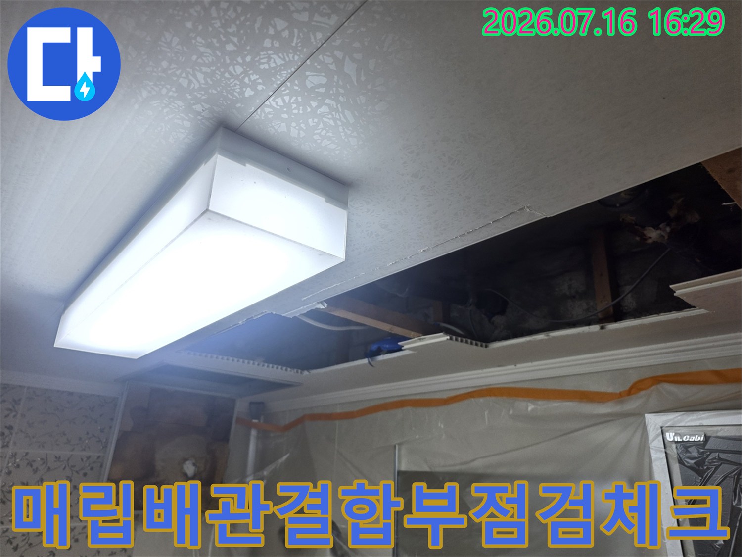 어두운 천장 내부 공간에서 배수 배관의 상태를 확인하는 모습