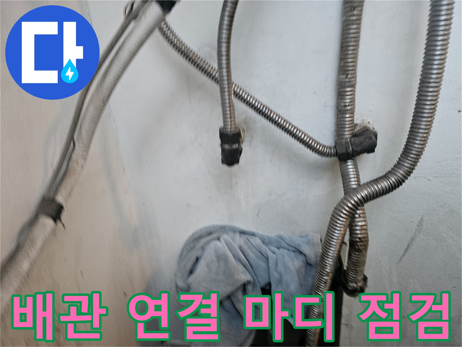 보일러 하단부의 은색 유연 배관과 벽체 연결 부위 사진입니다.