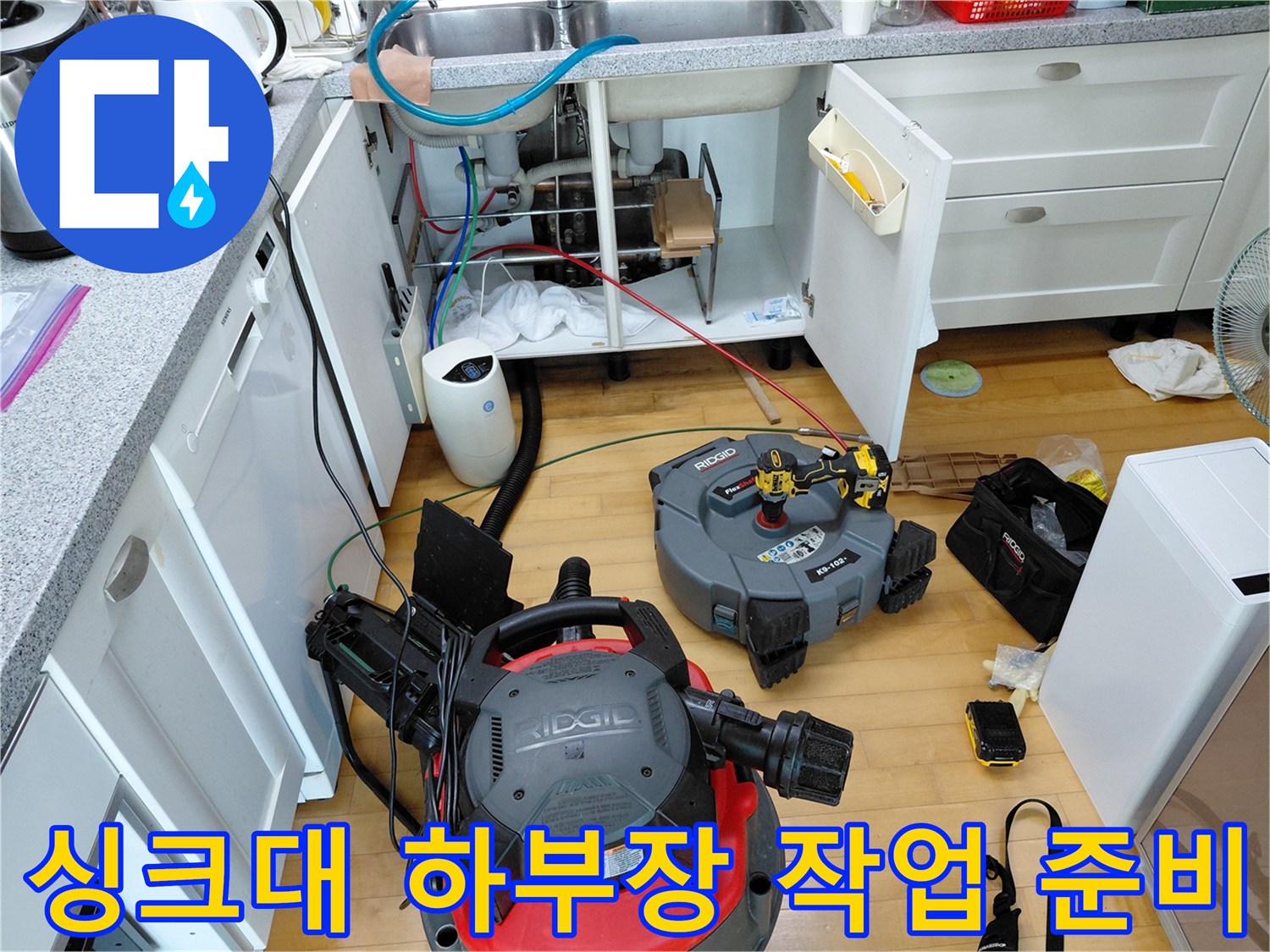 싱크대 아래 배관 청소를 위해 배치된 석션 장비와 공구들