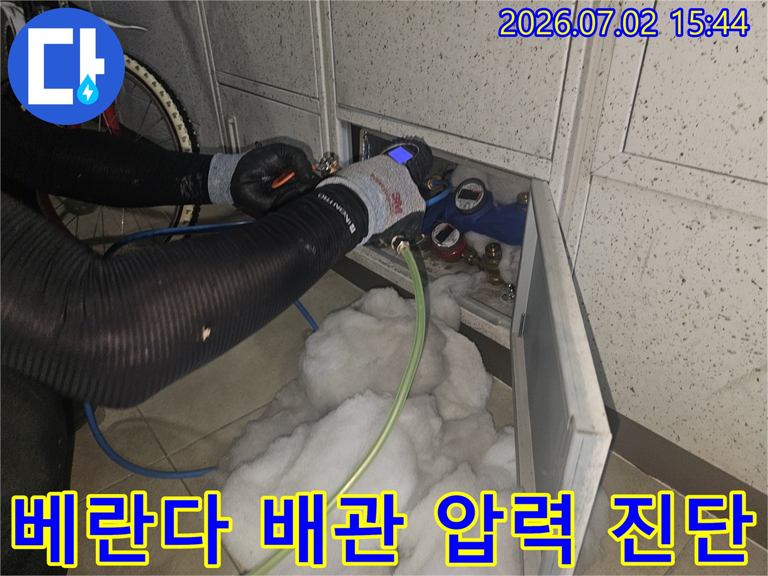 누수-전문가가-베란다-배관에-정밀-압력-측정-장비를-연결하여-누수-여부를-확인하는-모습