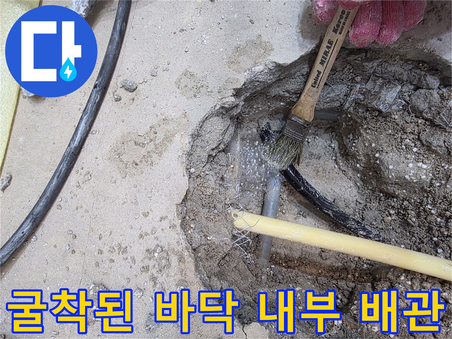 흙과 콘크리트 사이로 보이는 노출된 수도 배관과 호스