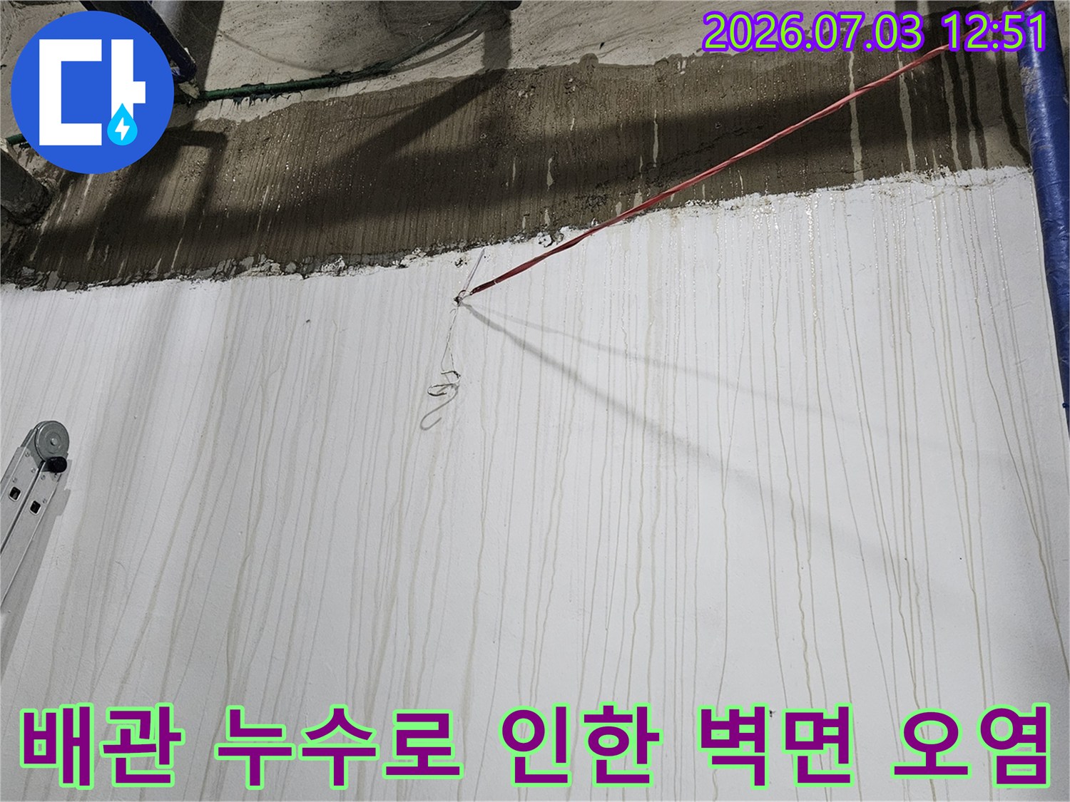 파란색 배관 두 줄이 세로로 놓여 있고 그 옆 하얀 벽면에 물이 흘러내린 자국들이 길게 남은 지하 현장 사진