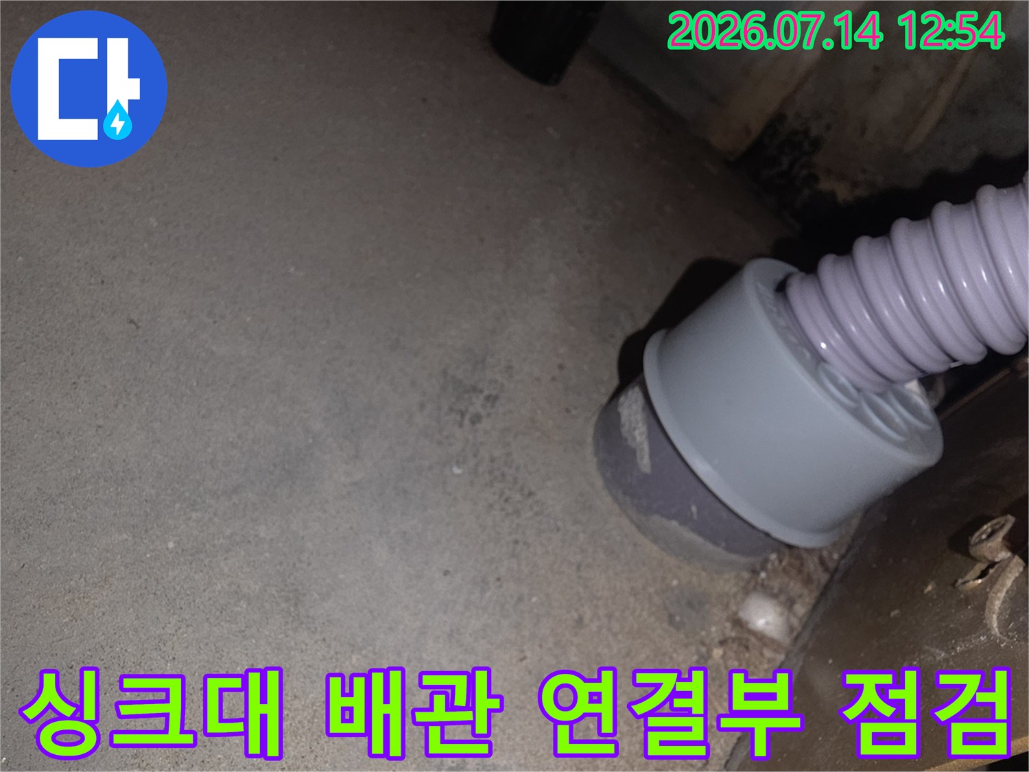 싱크대 하부의 회색 플라스틱 배관 연결 부위를 근접 촬영한 사진