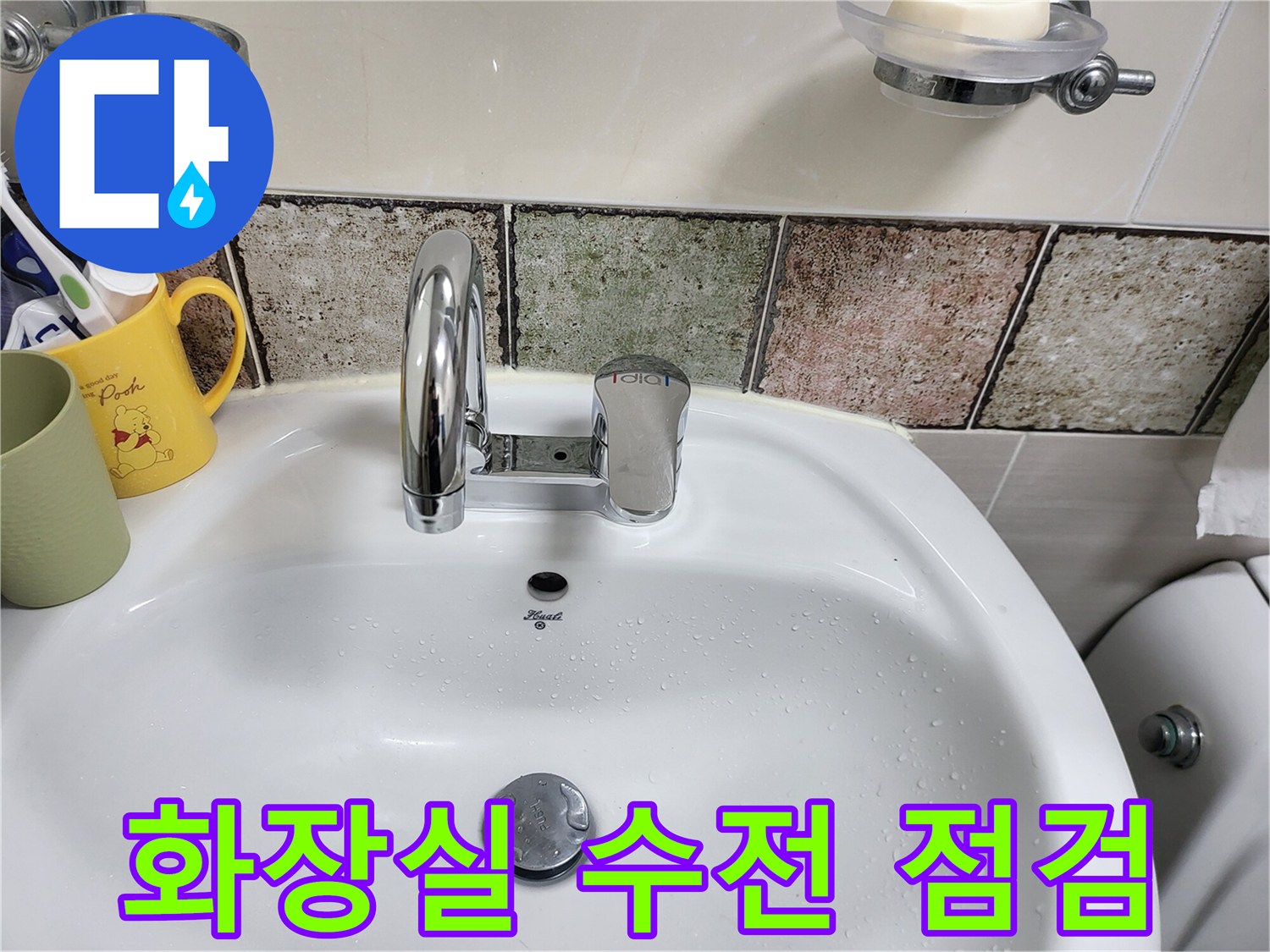 세면대에 설치된 은색 수전과 타일 벽면 사진입니다.