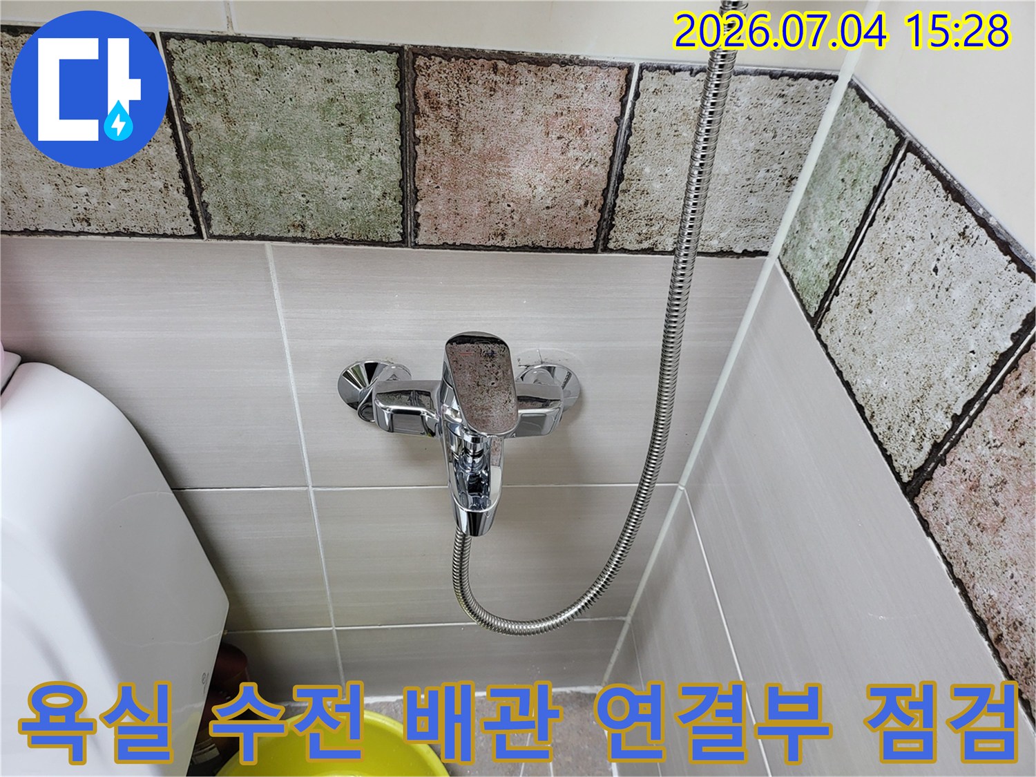 화장실 벽면 타일과 샤워기 호스 연결부의 상세 모습