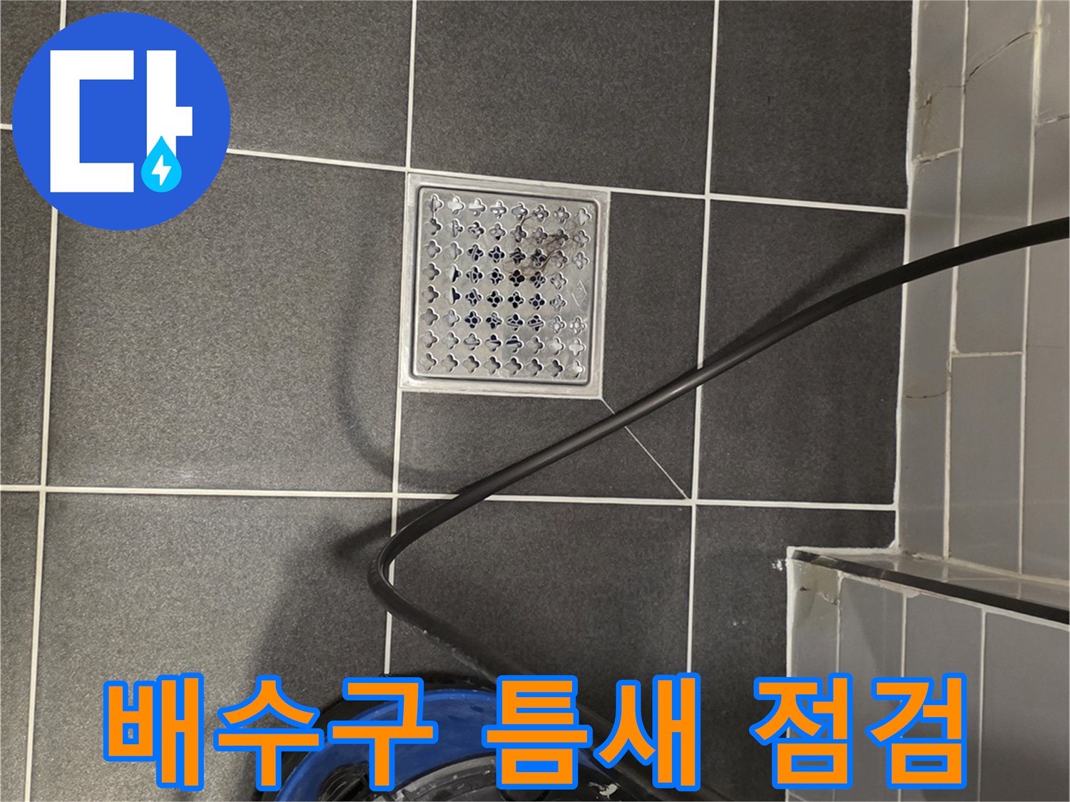 어두운 회색 타일과 금속 배수구 덮개의 상세 사진
