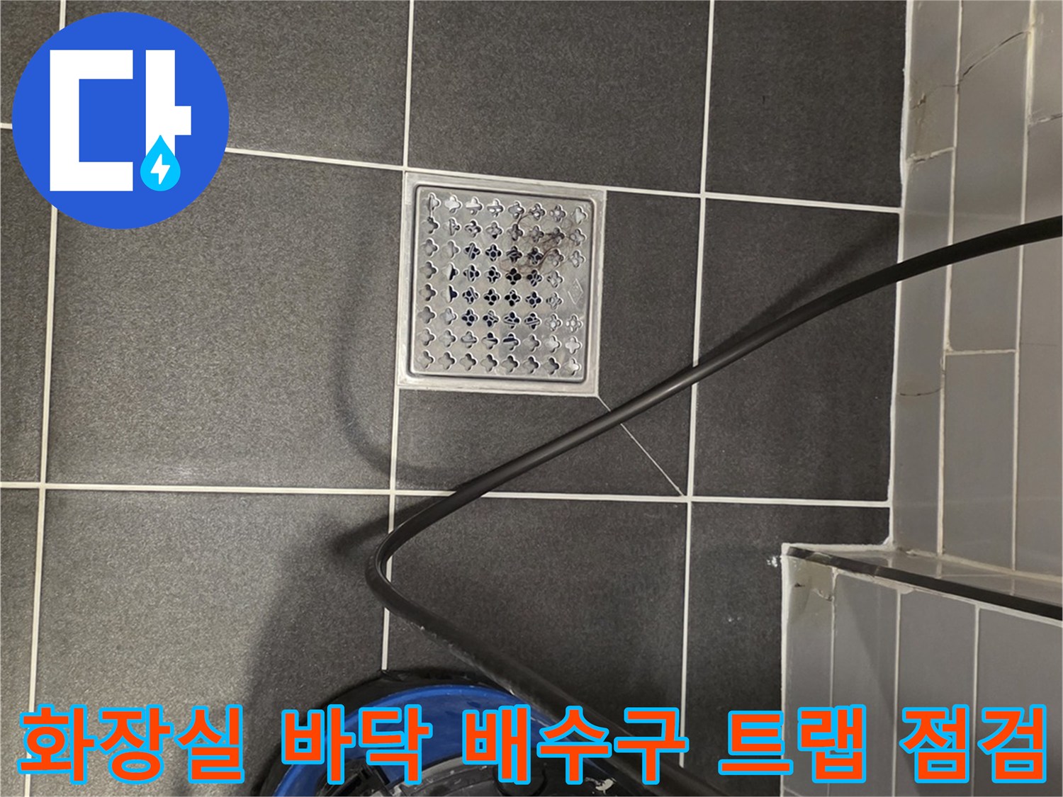 타일 바닥의 금속 배수구와 옆에 놓인 작업용 장비