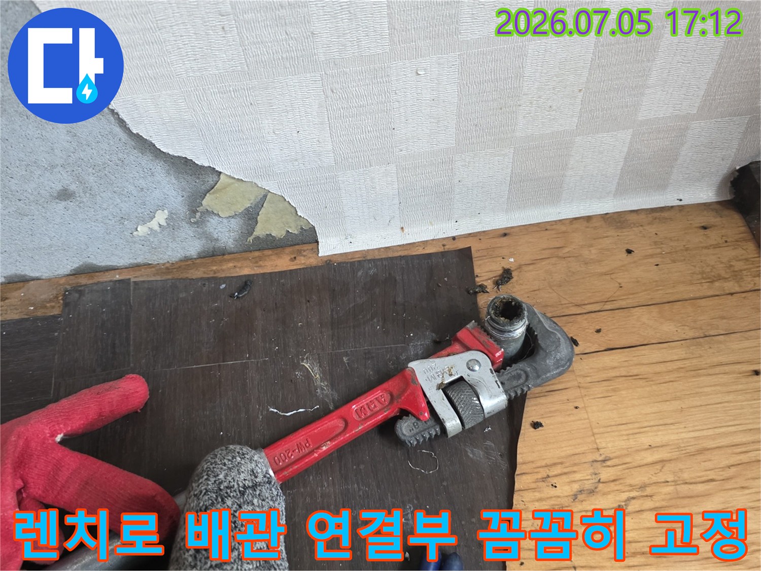 전문가용 파이프 렌치를 사용하여 노출된 금속 배관을 체결하는 상세 모습
