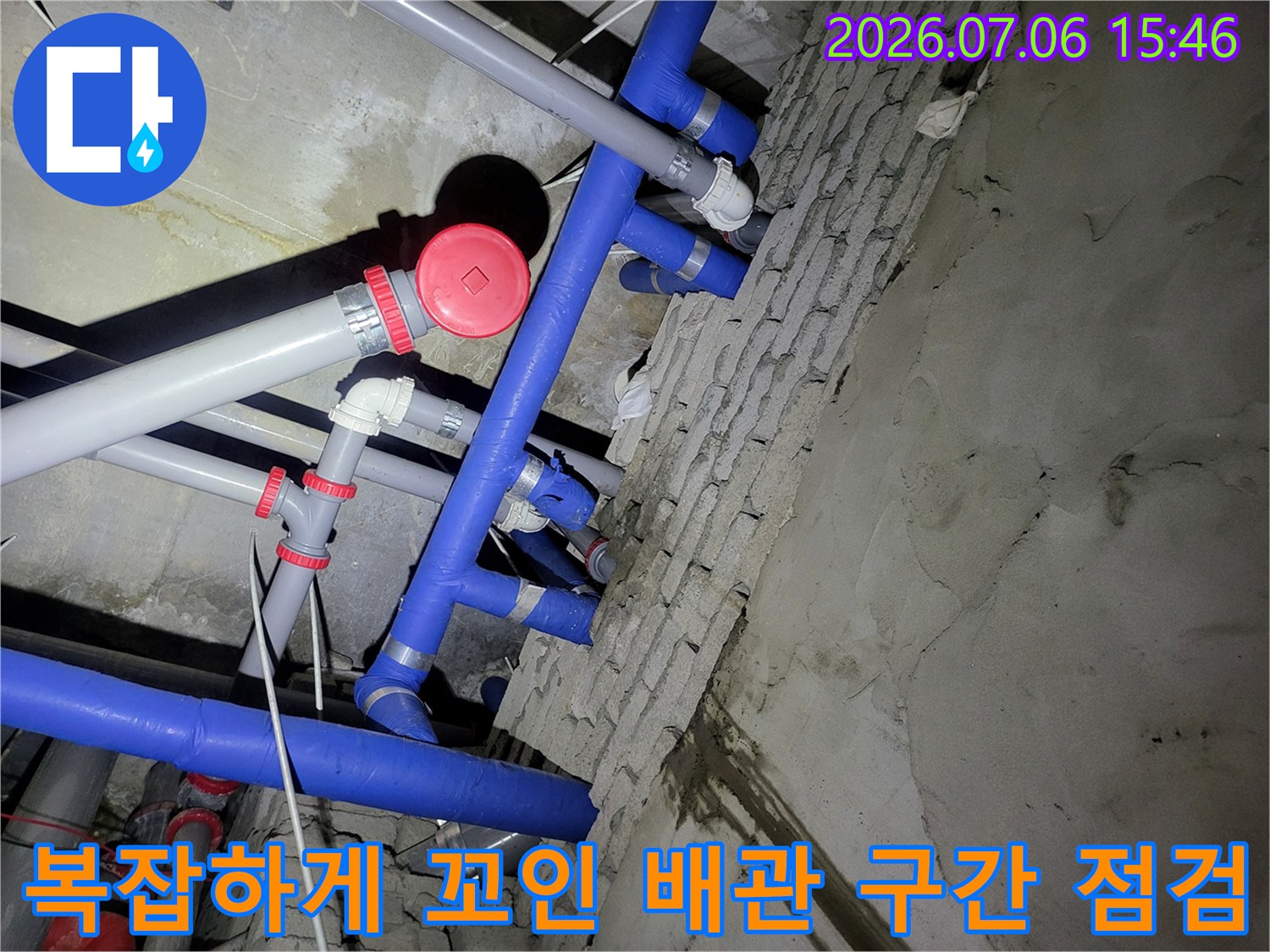 파란색과 회색이 혼재된 천장 내 수직 및 수평 배관들