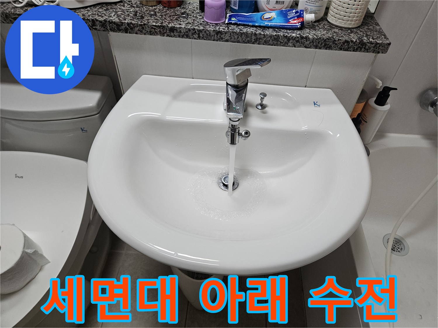 하얀색 세면대 밑에 설치된 은색 수전 부품입니다.