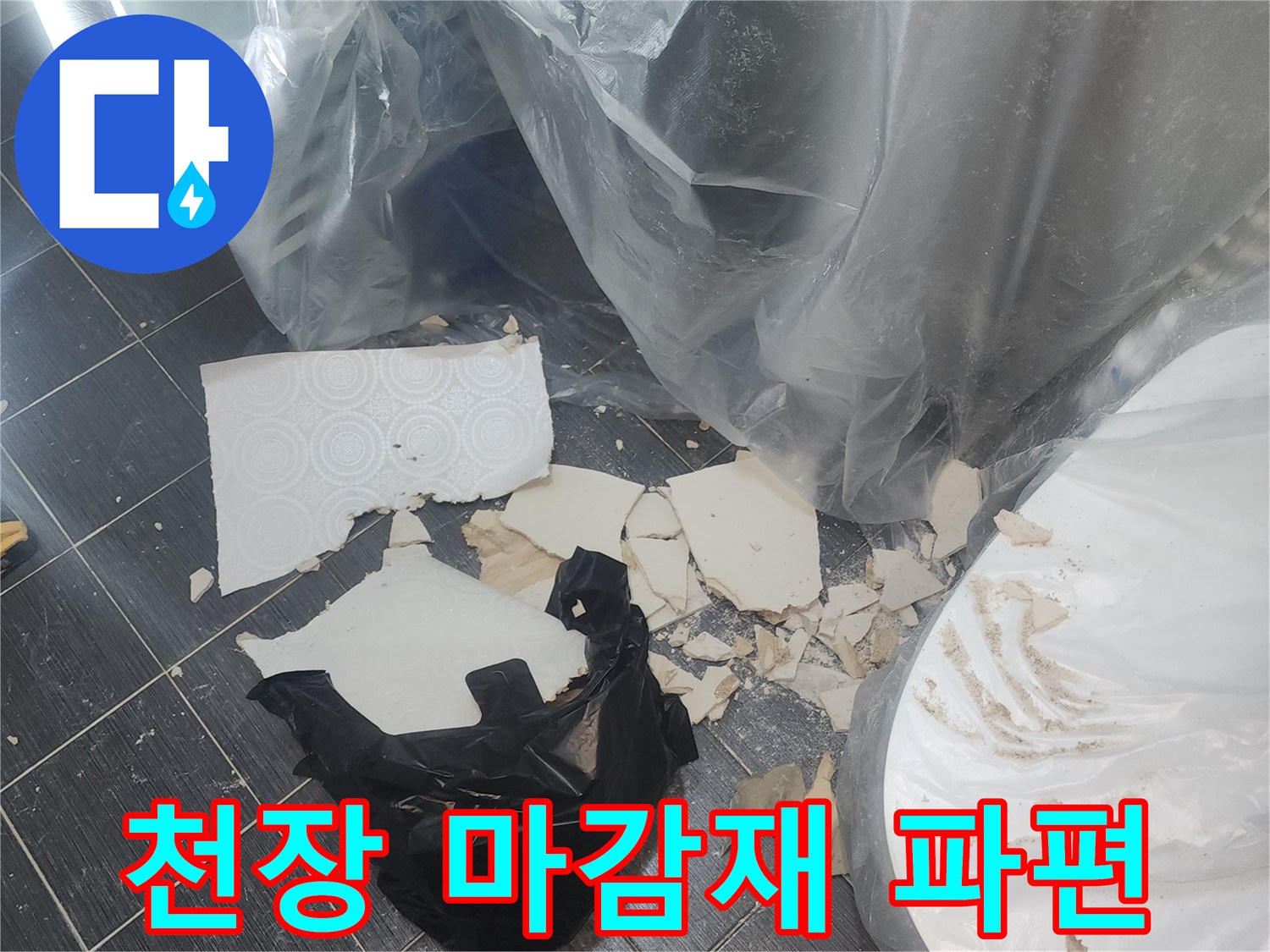 바닥에 흩어진 하얀색 천장재 조각과 검은 비닐