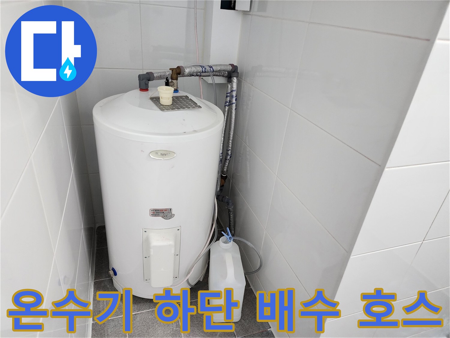 온수기 아래로 연결된 투명 호스와 배수통의 모습입니다.