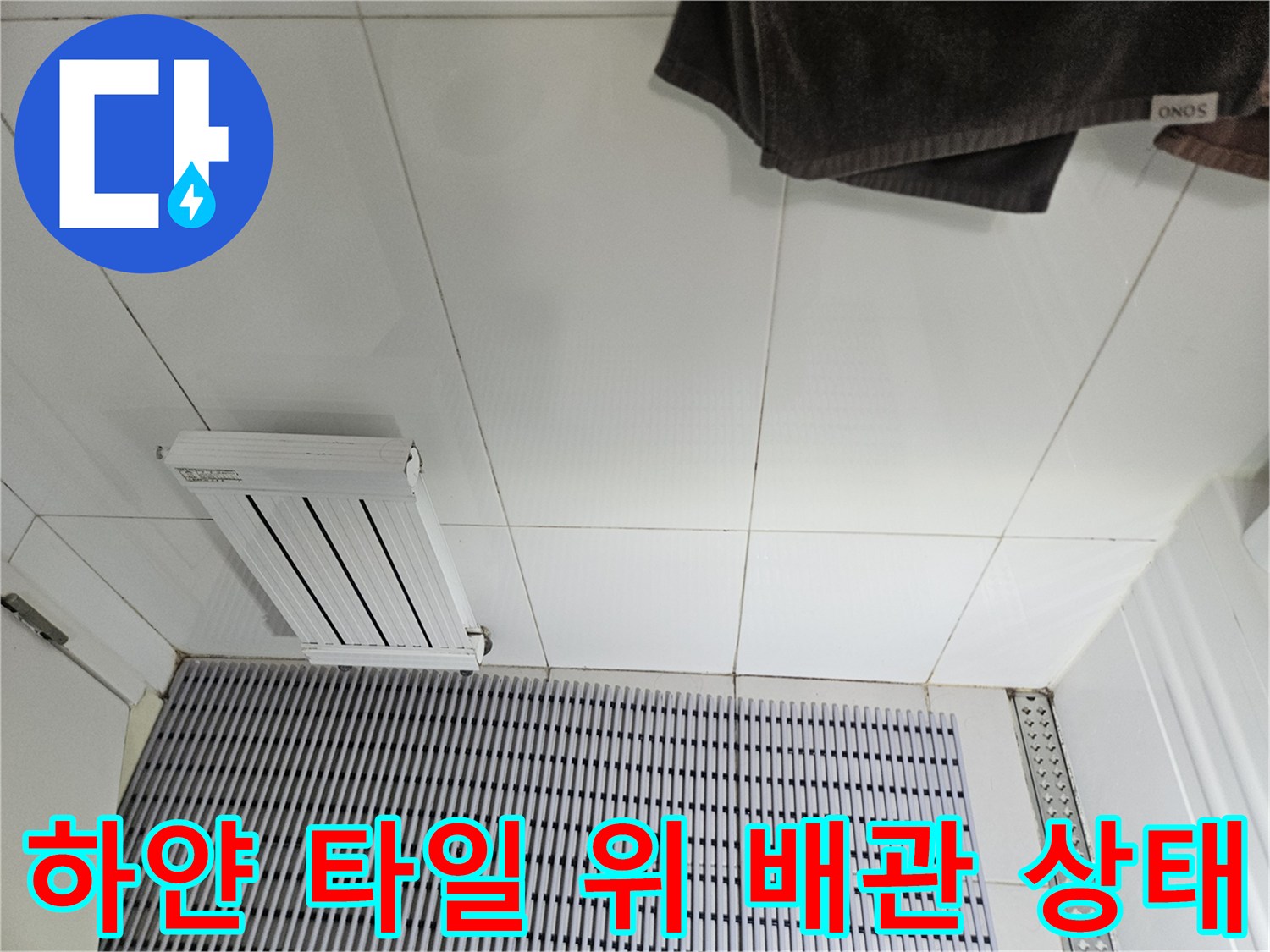 하얀색-타일-바닥-위에-놓여있는-에어컨-배수-라인