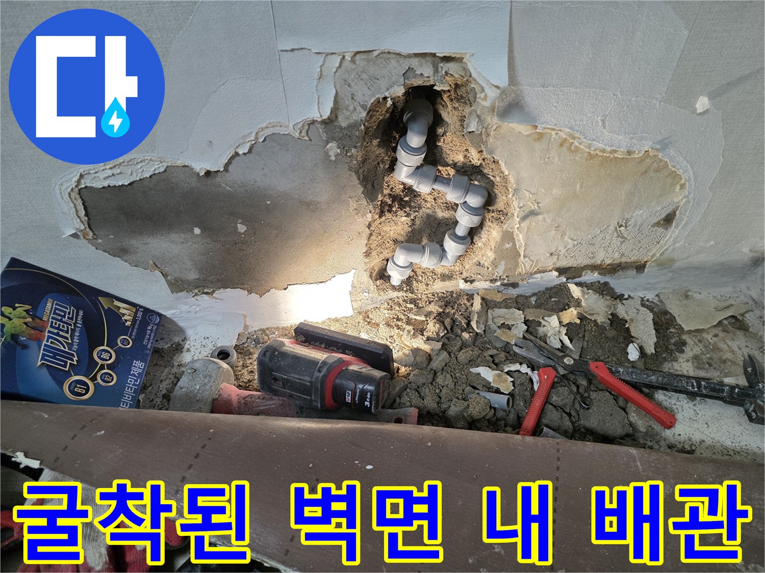 누수가 확인된 벽면 내부의 노출된 배관과 작업 도구들