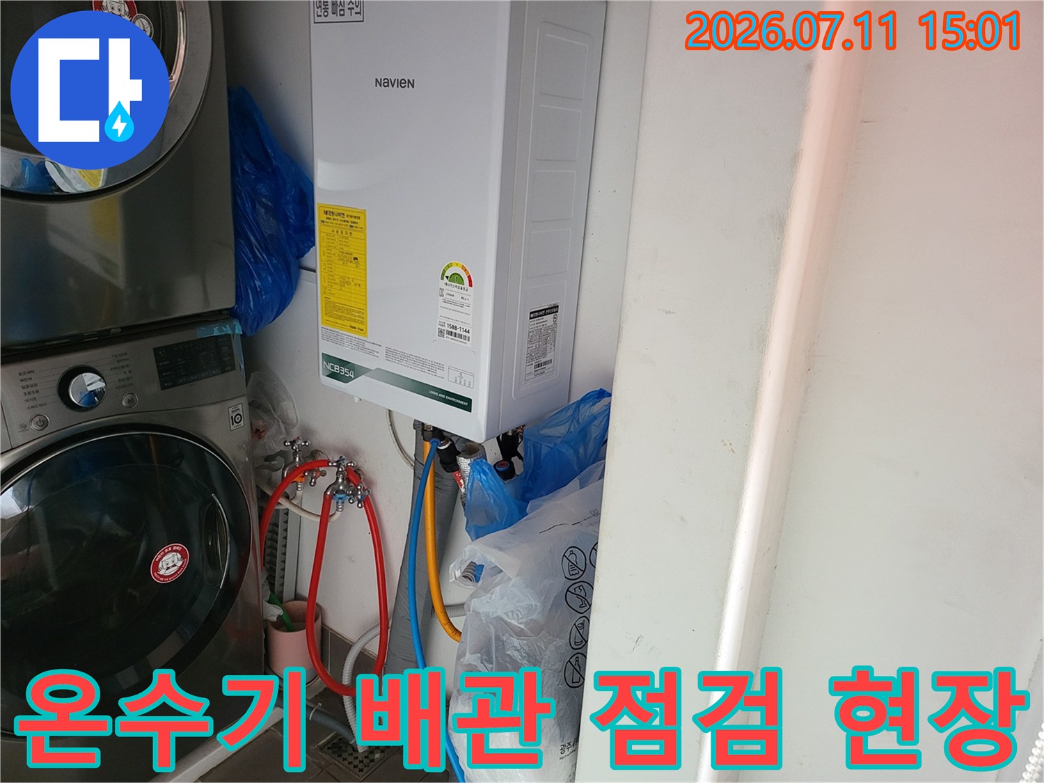 온수기 하단부 연결 부위의 노란색과 파란색 배관을 정밀 점검하는 모습