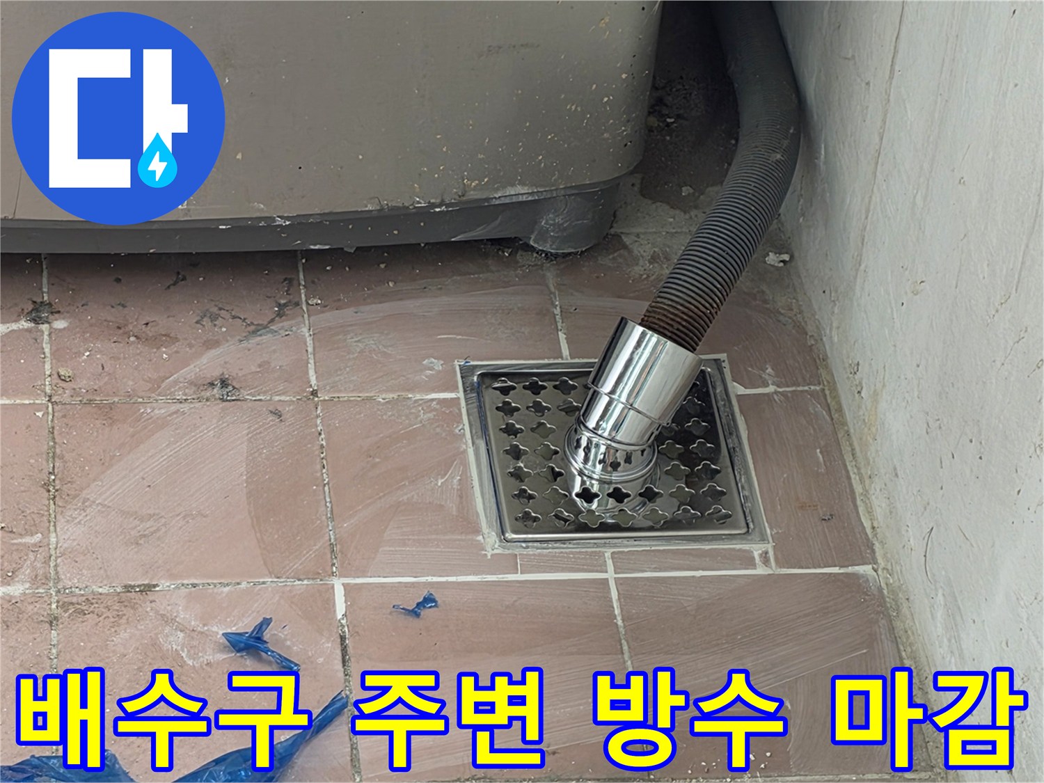타일 바닥에 매립된 스테인리스 배수 트랩과 세탁기 호스