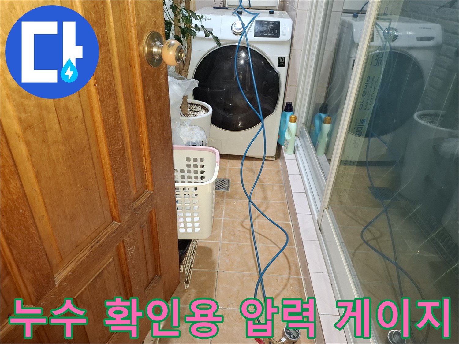 바닥 타일 위에 놓인 파란색 호스와 수압 측정 장치