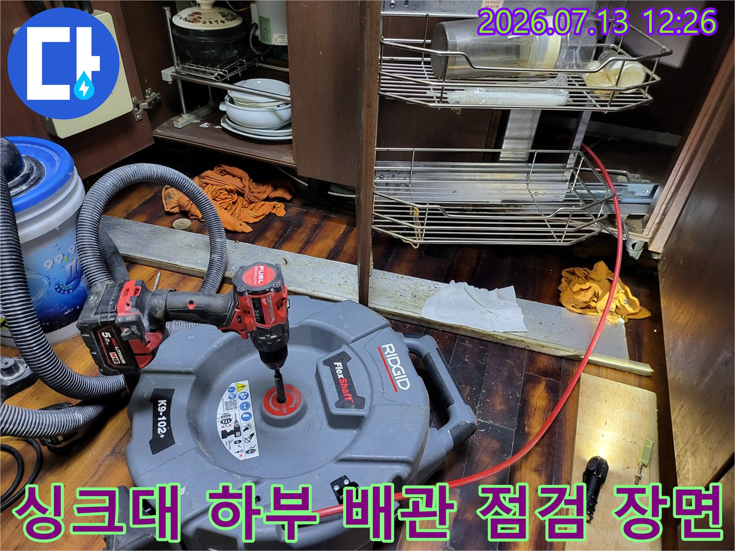 싱크대 하부 공간에서 전문 장비를 사용하여 배수관을 정밀 점검하는 모습