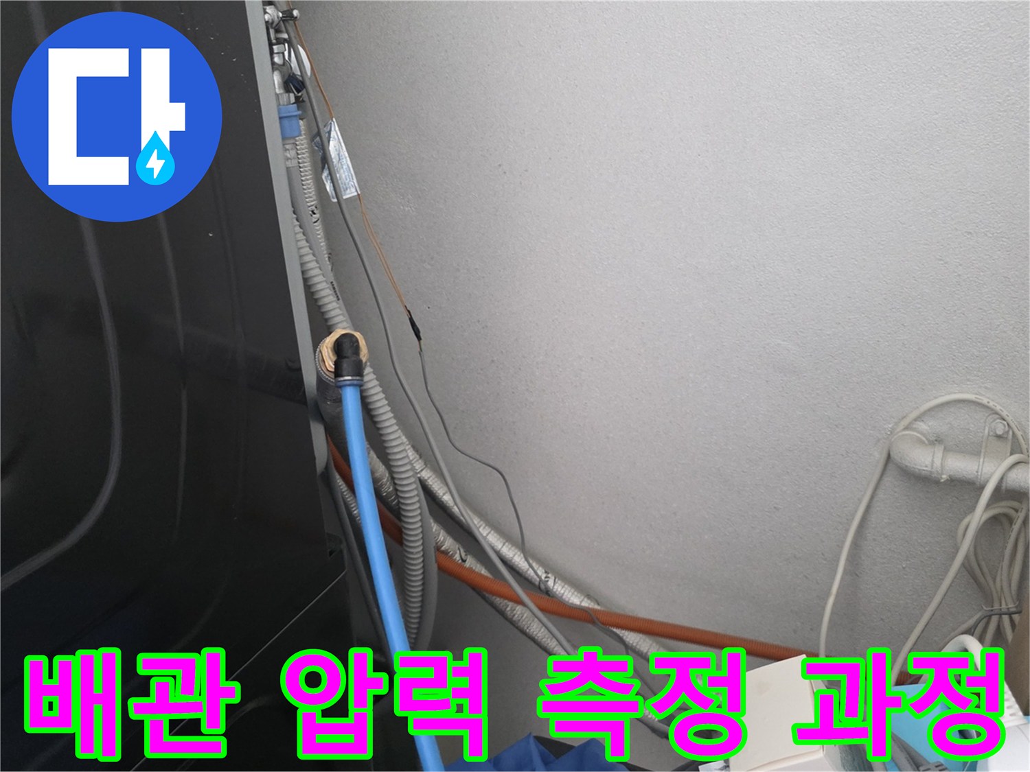 파란색 호스가 연결된 벽면 하단 배관 구조물