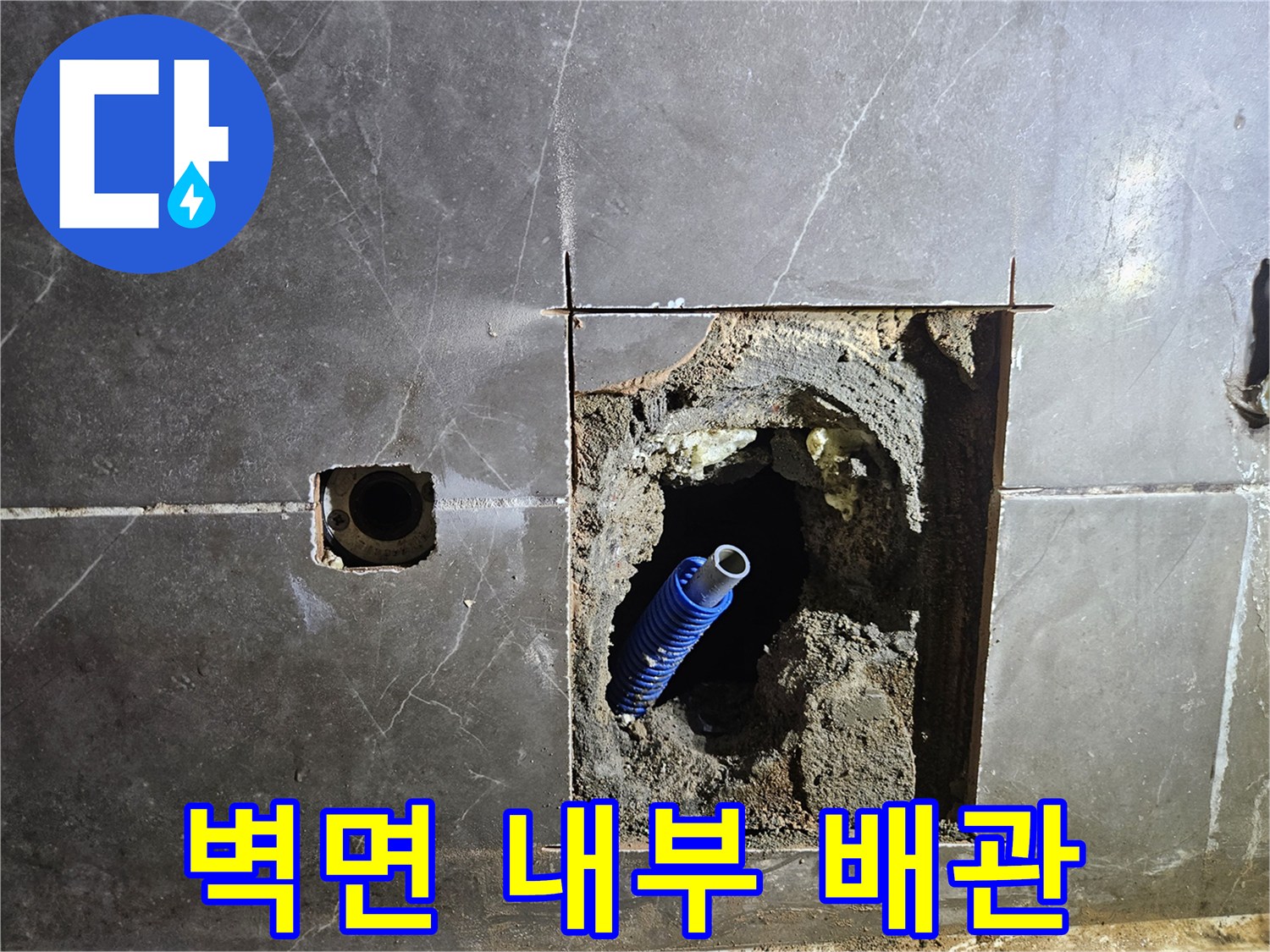 벽면을 파내어 드러난 파란색 배관과 젖은 콘크리트 벽체