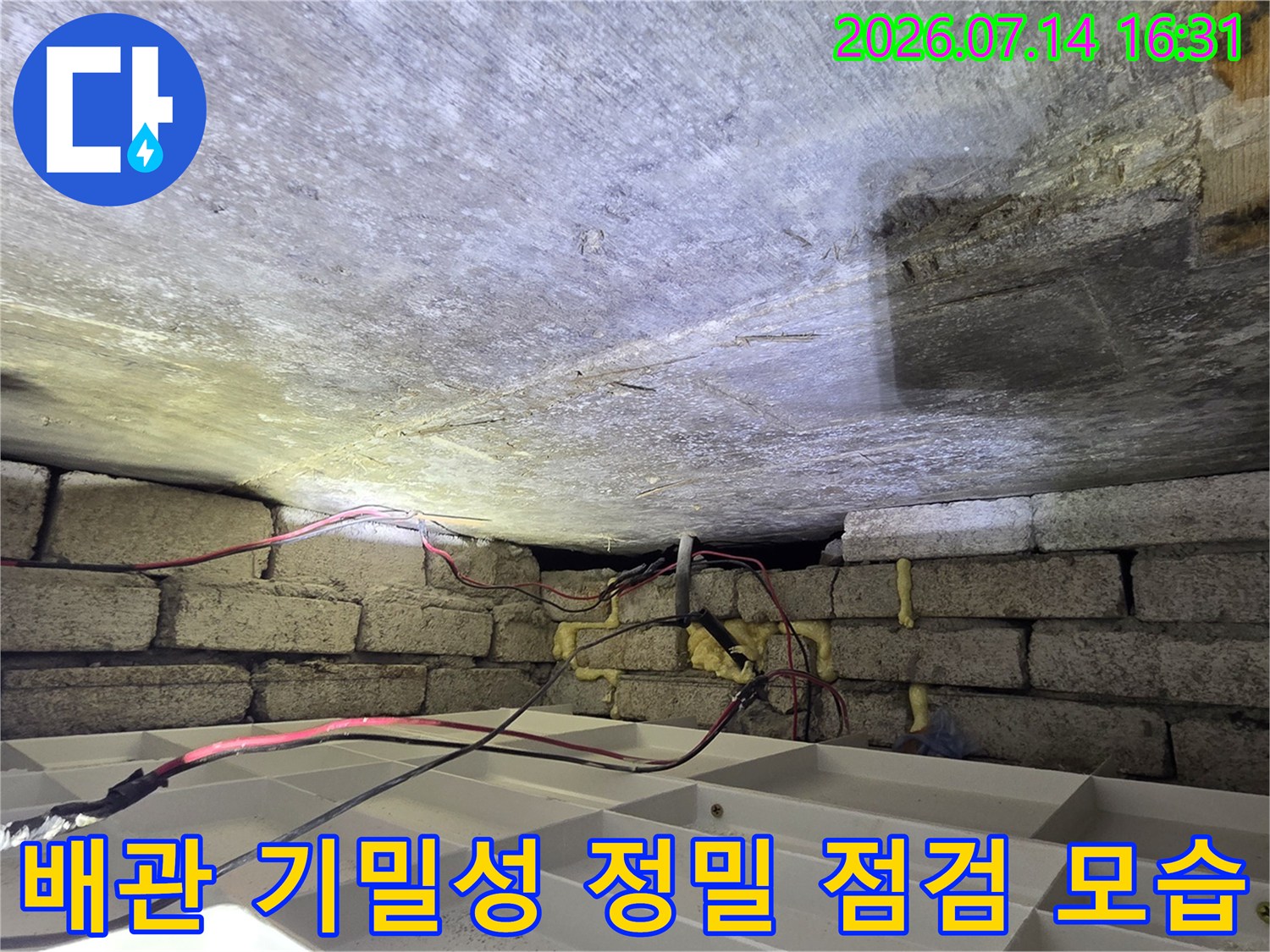 화장실 천장부 노출된 배관에 압력 테스트 장비를 연결한 상태의 사진