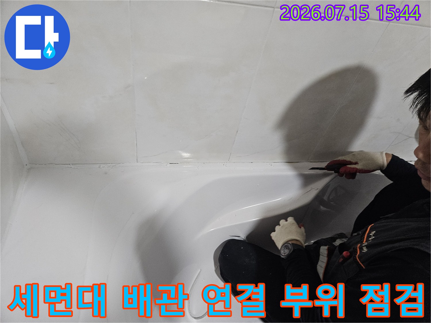 세면대 하단 공간에서 작업자가 누수 지점을 파악하는 장면
