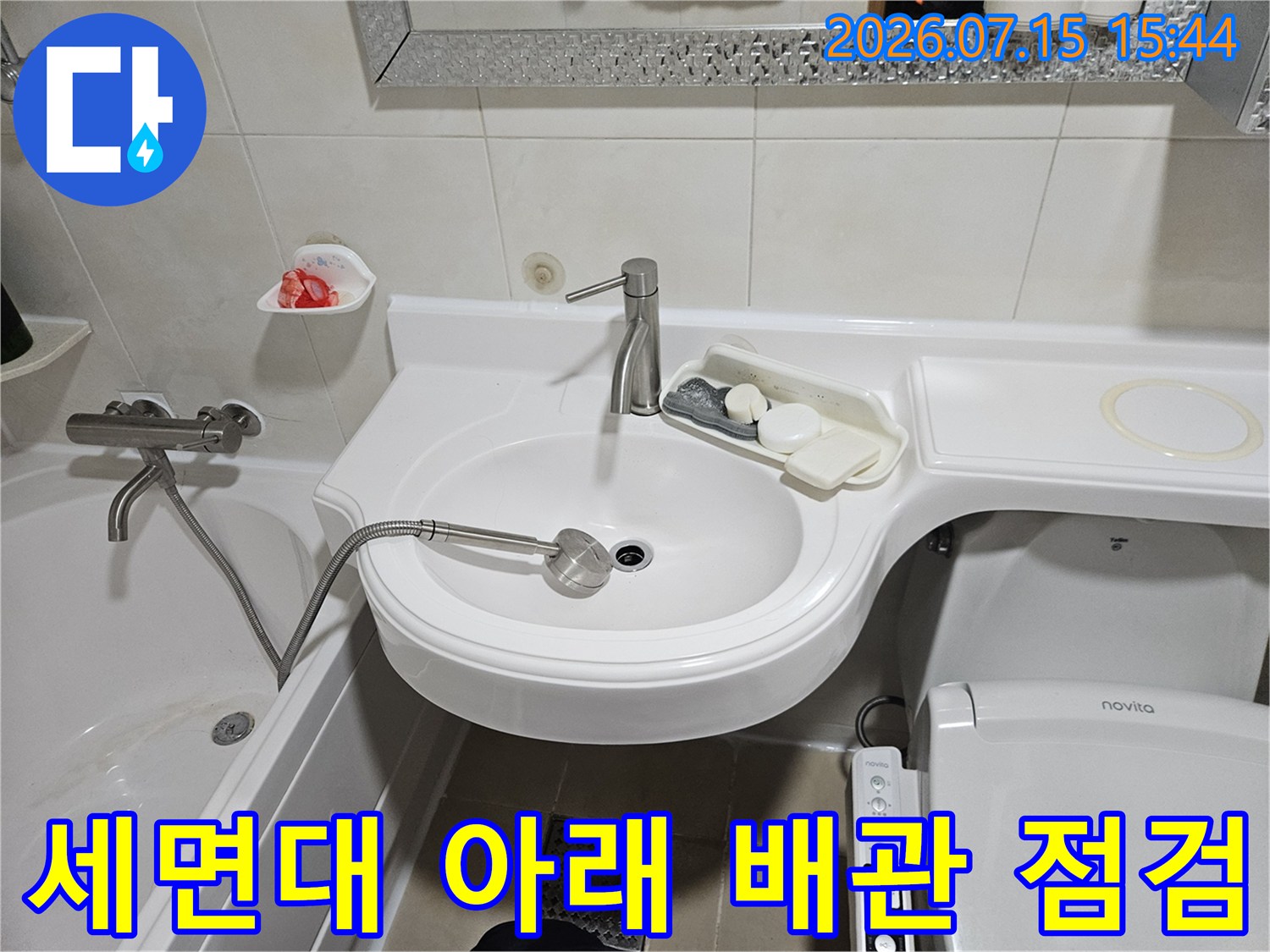 세면대 하부의 노출된 배관과 수전 부위를 점검하는 모습