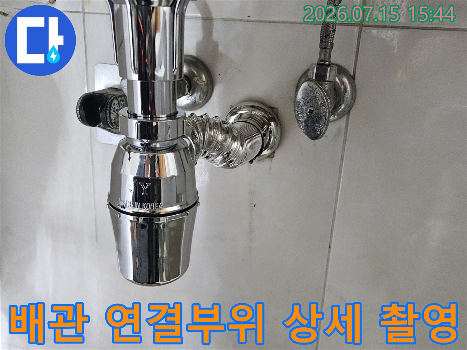 욕실 세면대 아래에 위치한 배관과 연결 부품의 근접 모습입니다.