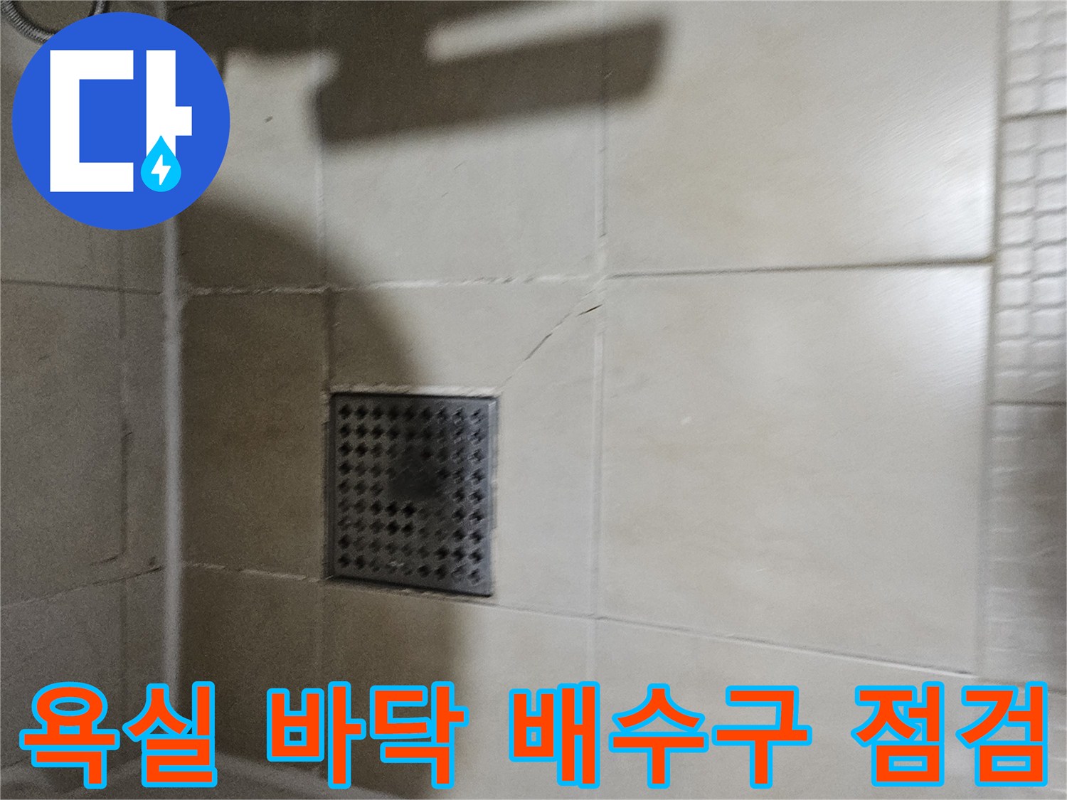화장실 바닥 배수구와 갈라진 타일 조각을 촬영한 사진입니다.