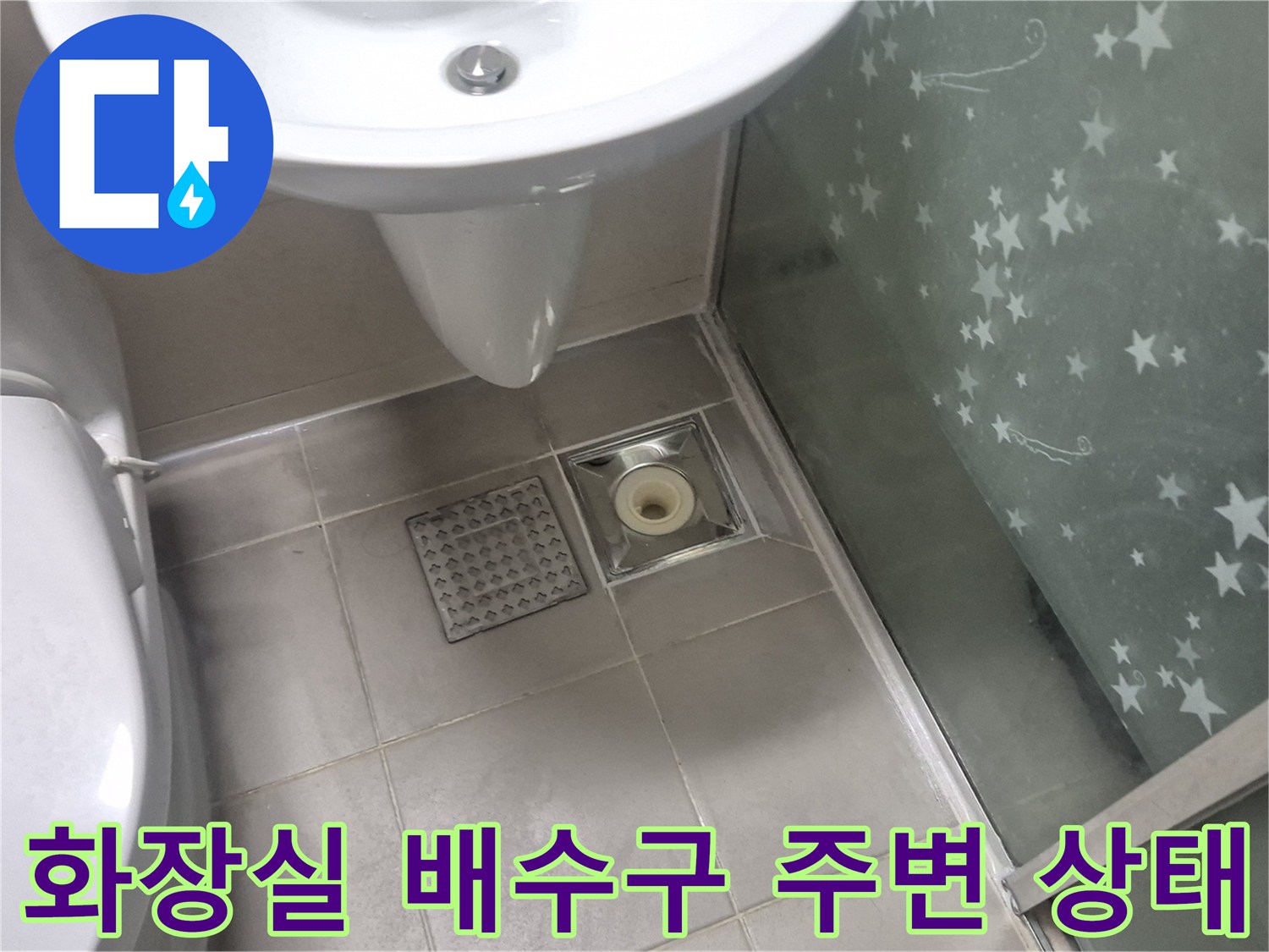 세면대 아래 배수구와 타일 바닥의 모습입니다.