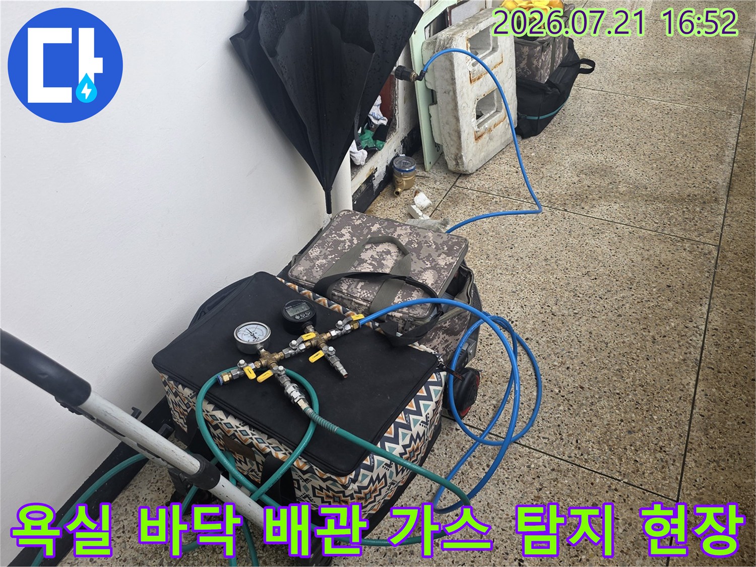파란색 호스가 연결된 가스 탐지 장비로 화장실 누수 위치를 정밀하게 파악하는 장면