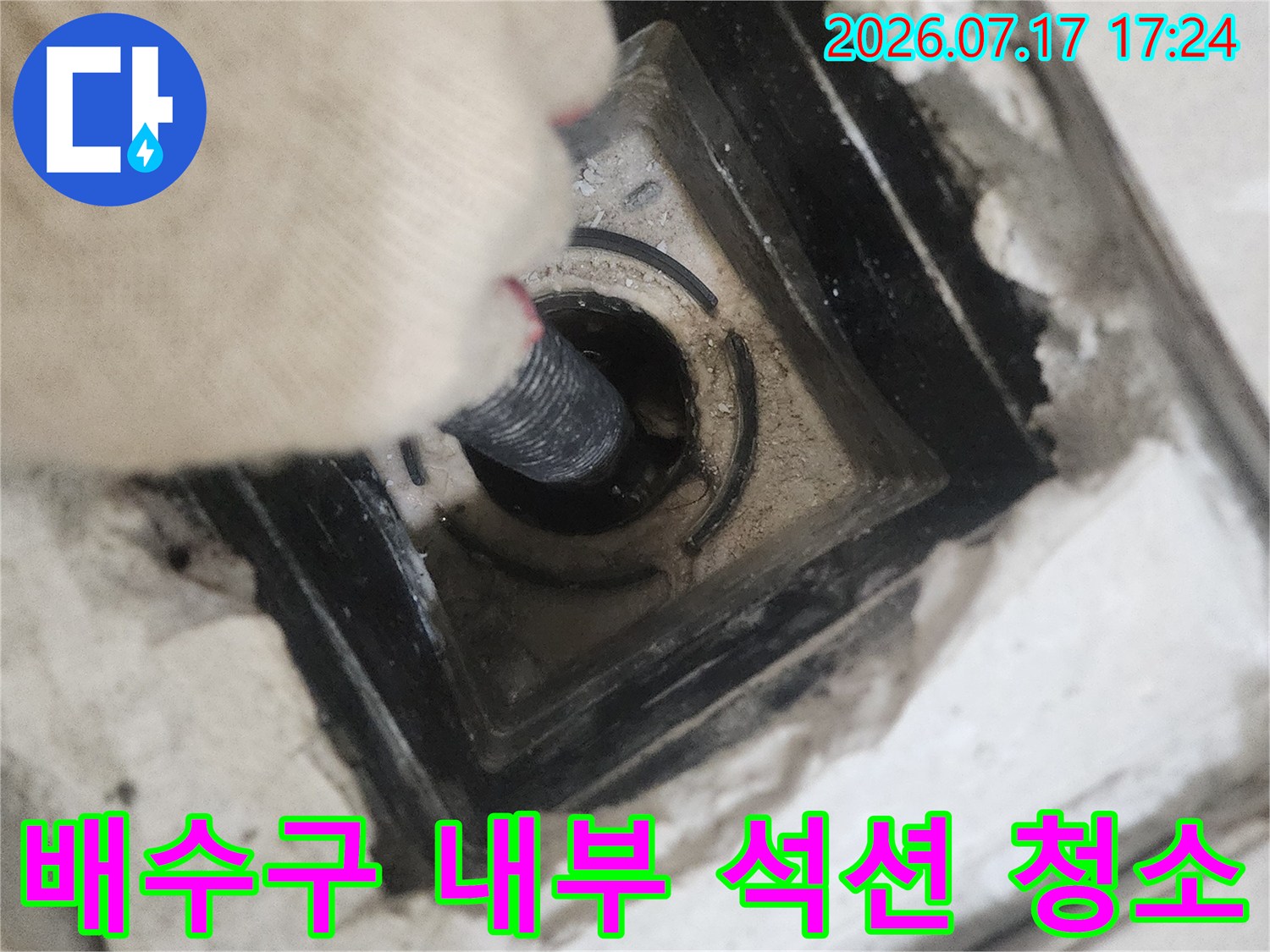 석션 기계로 배수구 내 오물 제거하는 장면