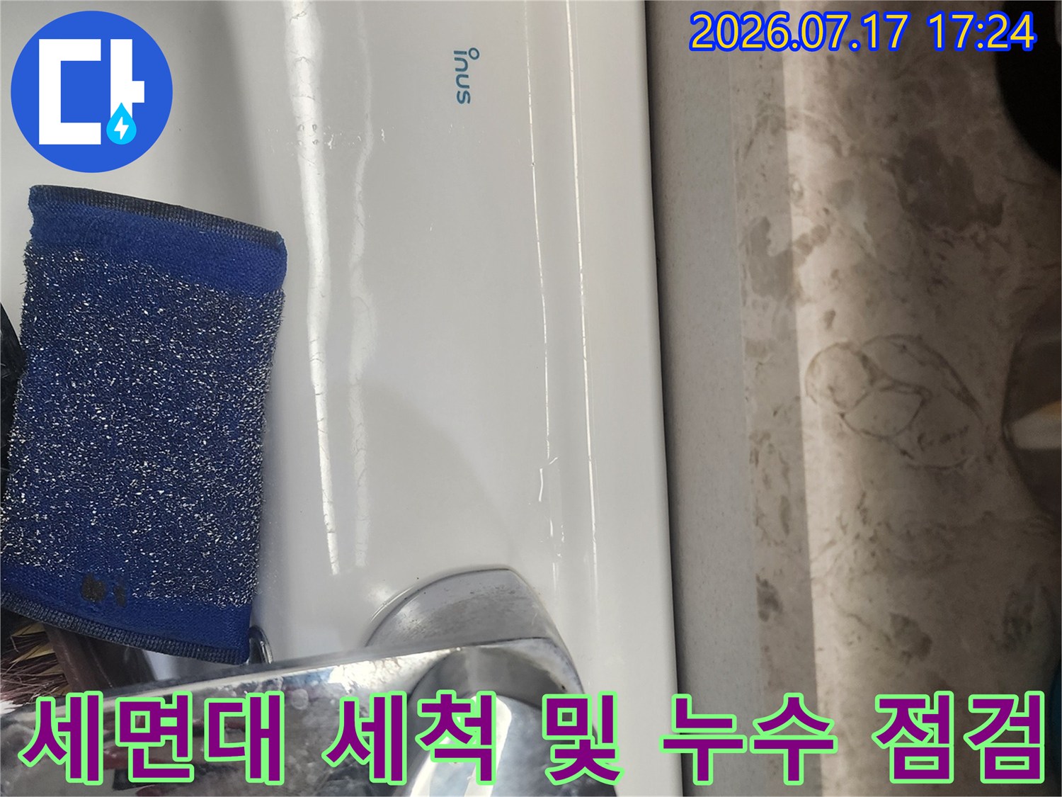 흰색 세면대에 놓인 파란색 수세미와 수도꼭지 점검 모습