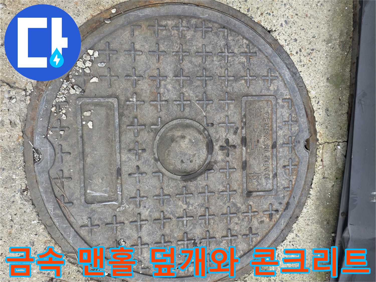 거친 콘크리트 바닥에 자리 잡은 철제 맨홀 덮개