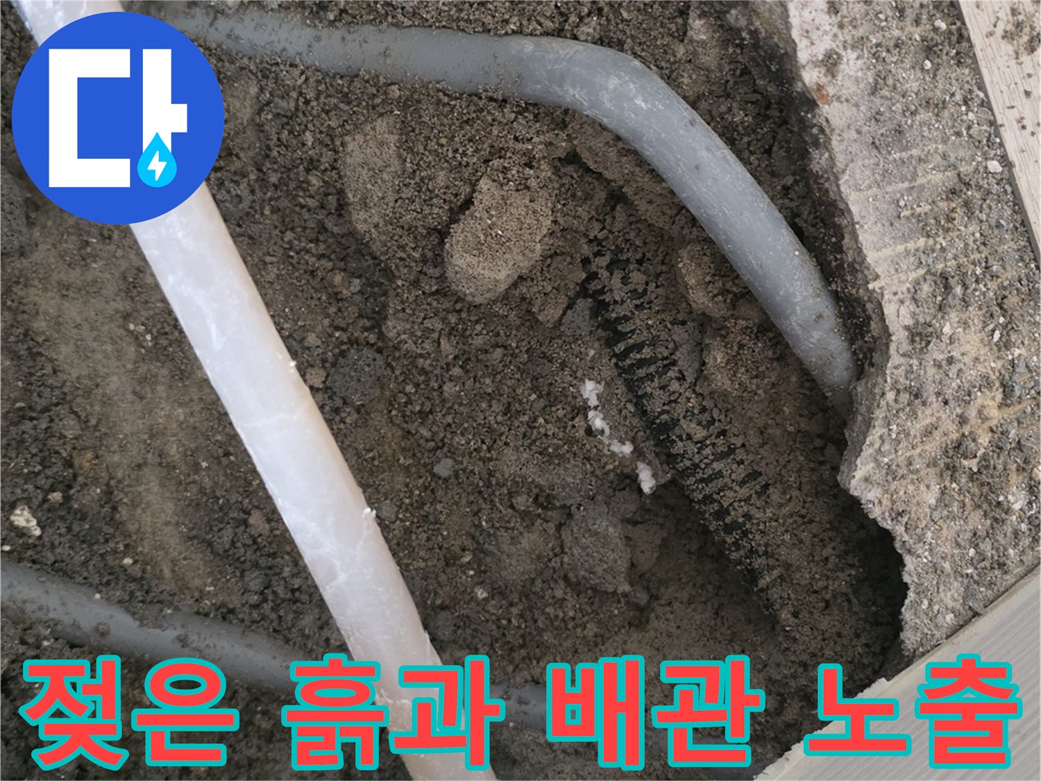 콘크리트 아래 젖어 있는 흙과 회색 배관의 모습