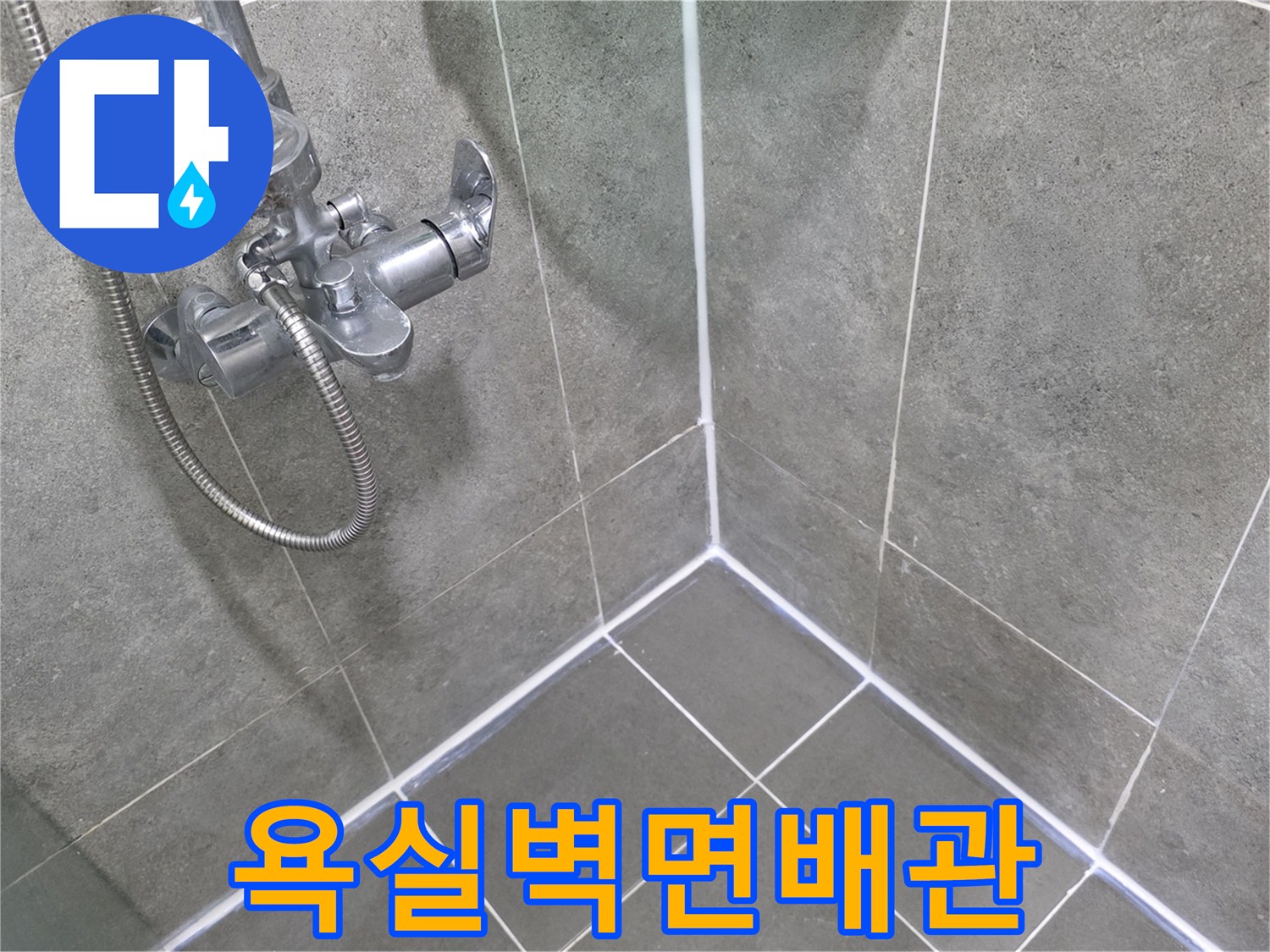 샤워기 수전과 은색 샤워 호스가 연결된 욕실 벽면