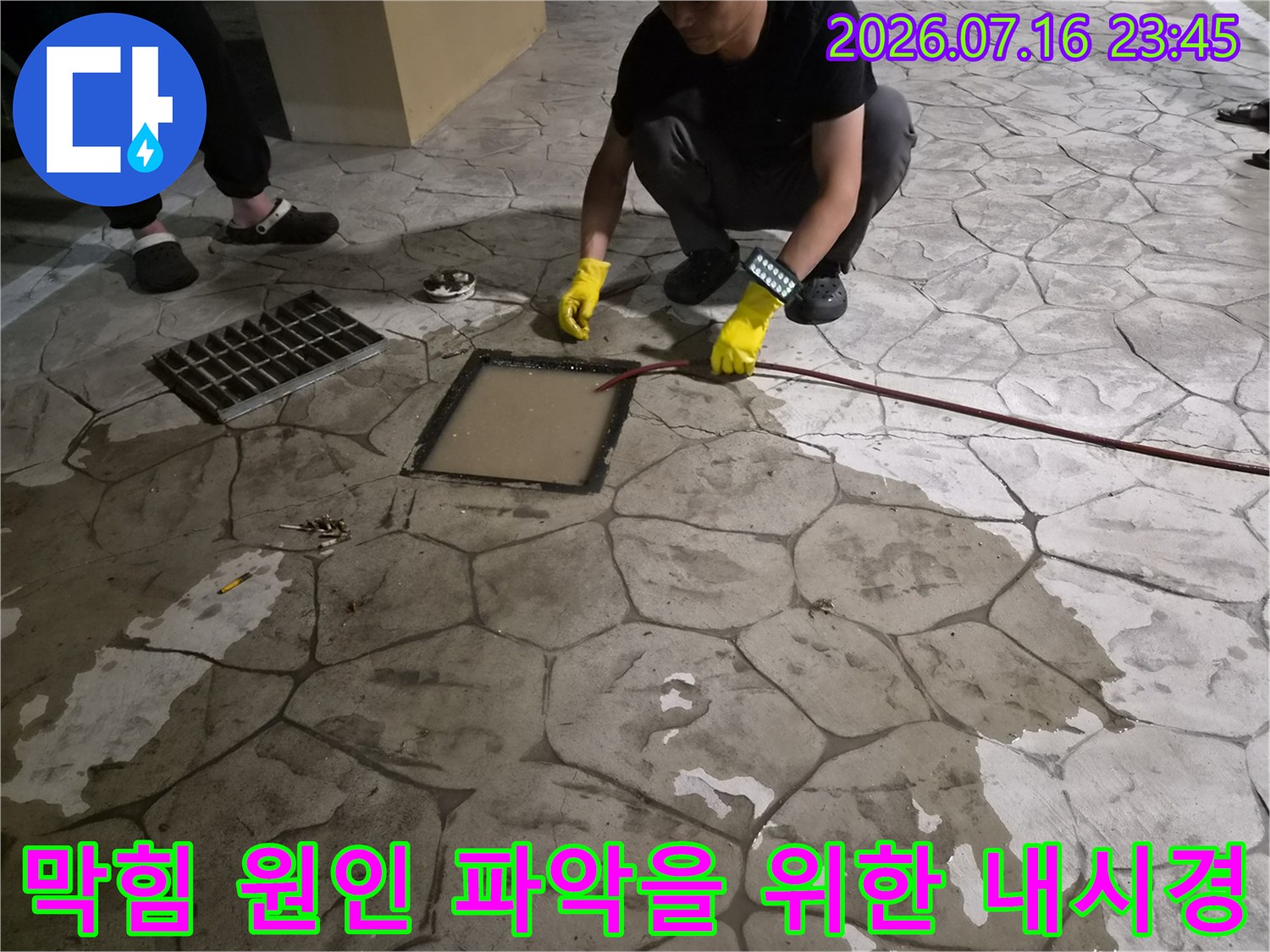 노란 장갑과 전문 장비를 갖춘 엔지니어가 배수구를 점검하는 모습