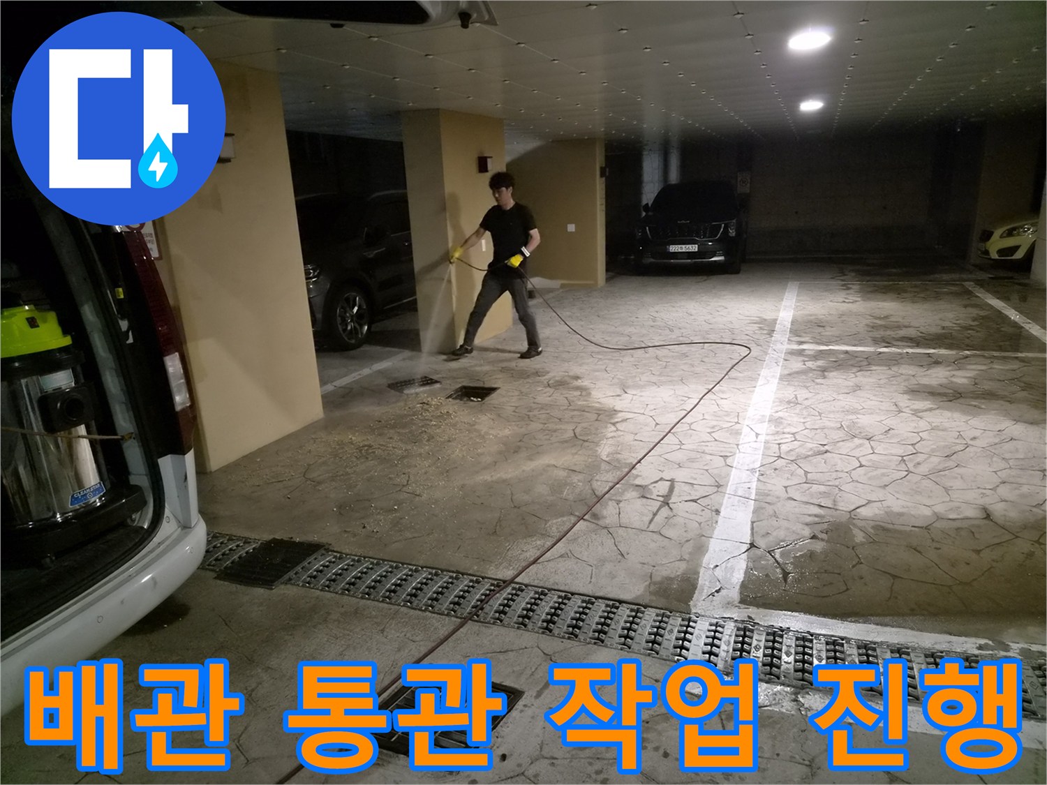 주차장 바닥의 막힌 배관을 뚫기 위해 전동 장비를 사용하는 모습