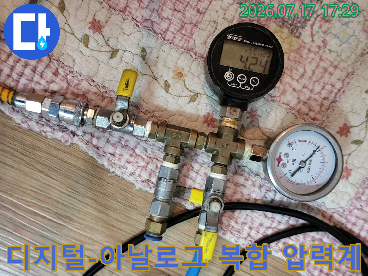 금속 밸브와 파란색 호스가 연결된 정밀 배관 압력 측정 장치